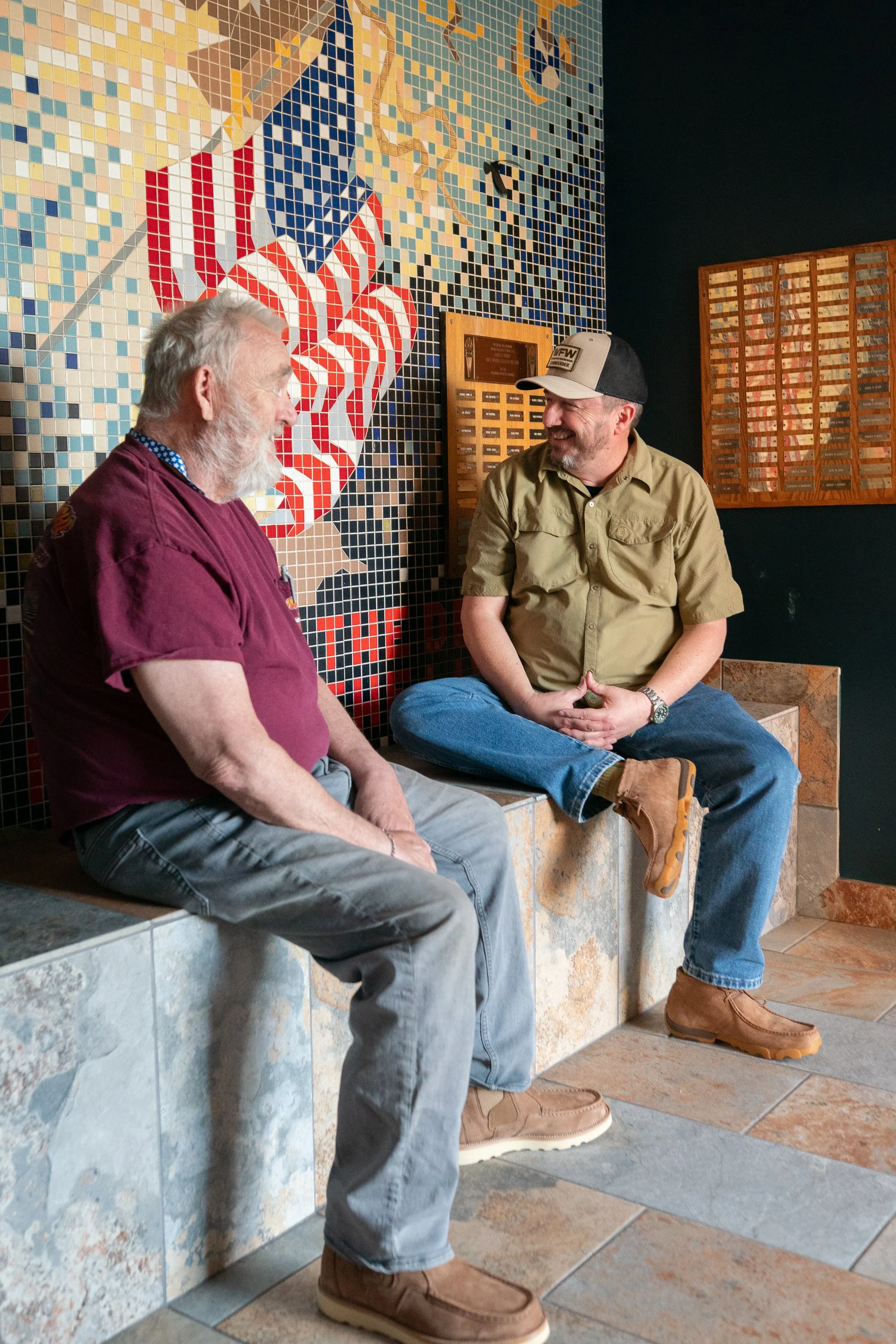 Veterans sitting near a mosaic wall inside a VFW hall during a brand campaign