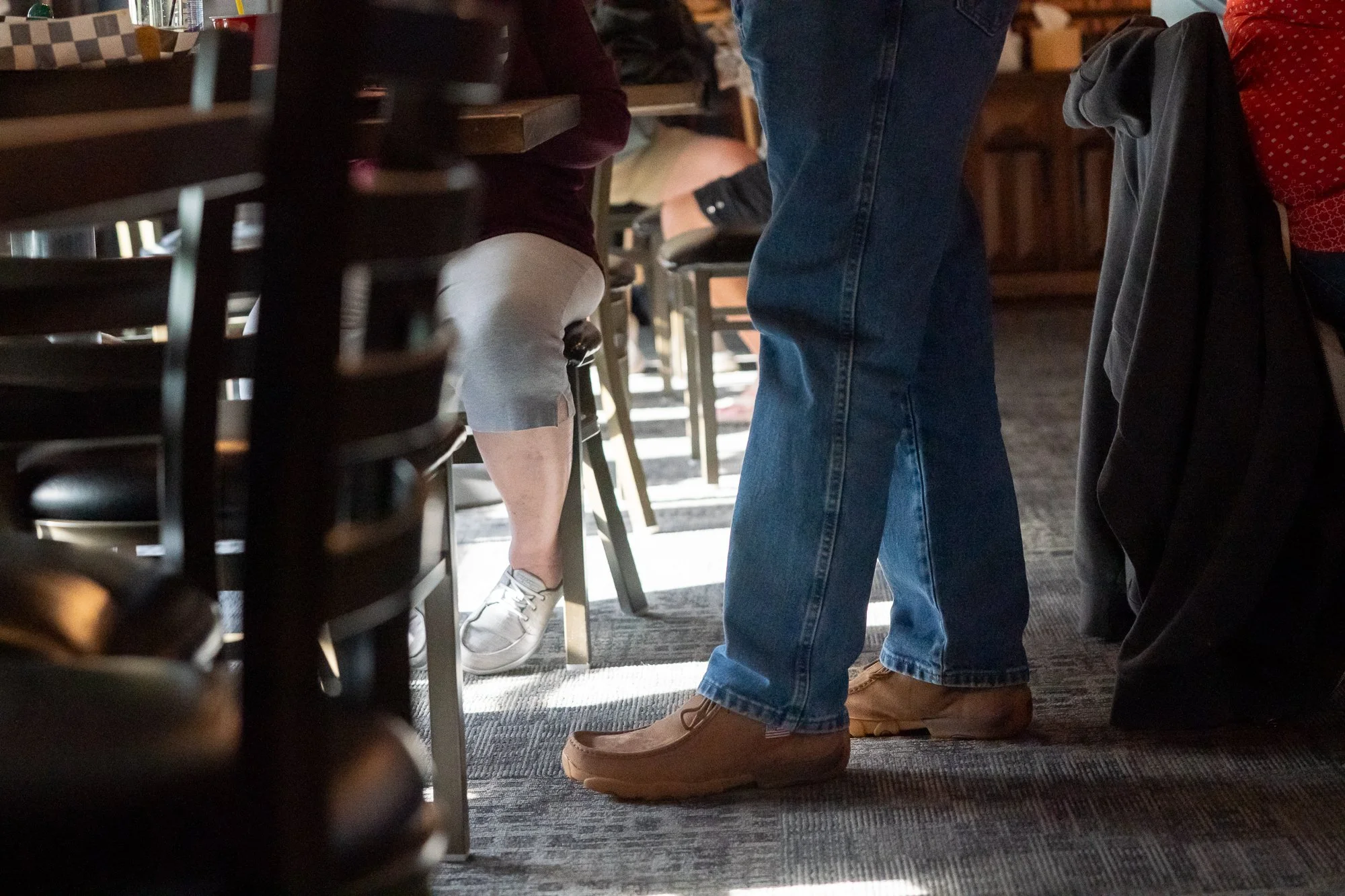 Twisted X shoes worn by people standing and sitting inside a VFW hall during a brand campaign