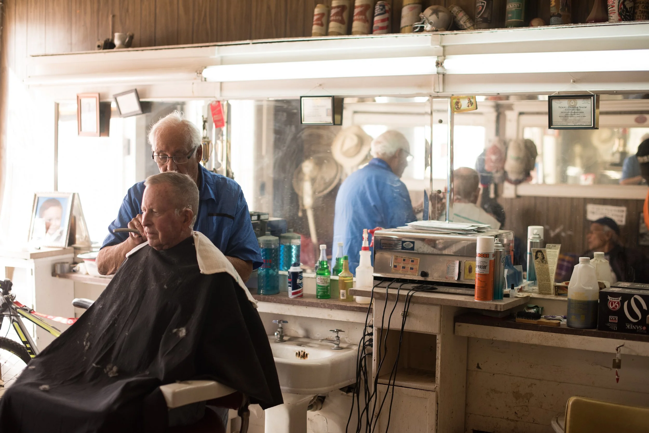 Mirror reflection of barber and client inside a compact workstation in a Marfa, Texas barbershop.