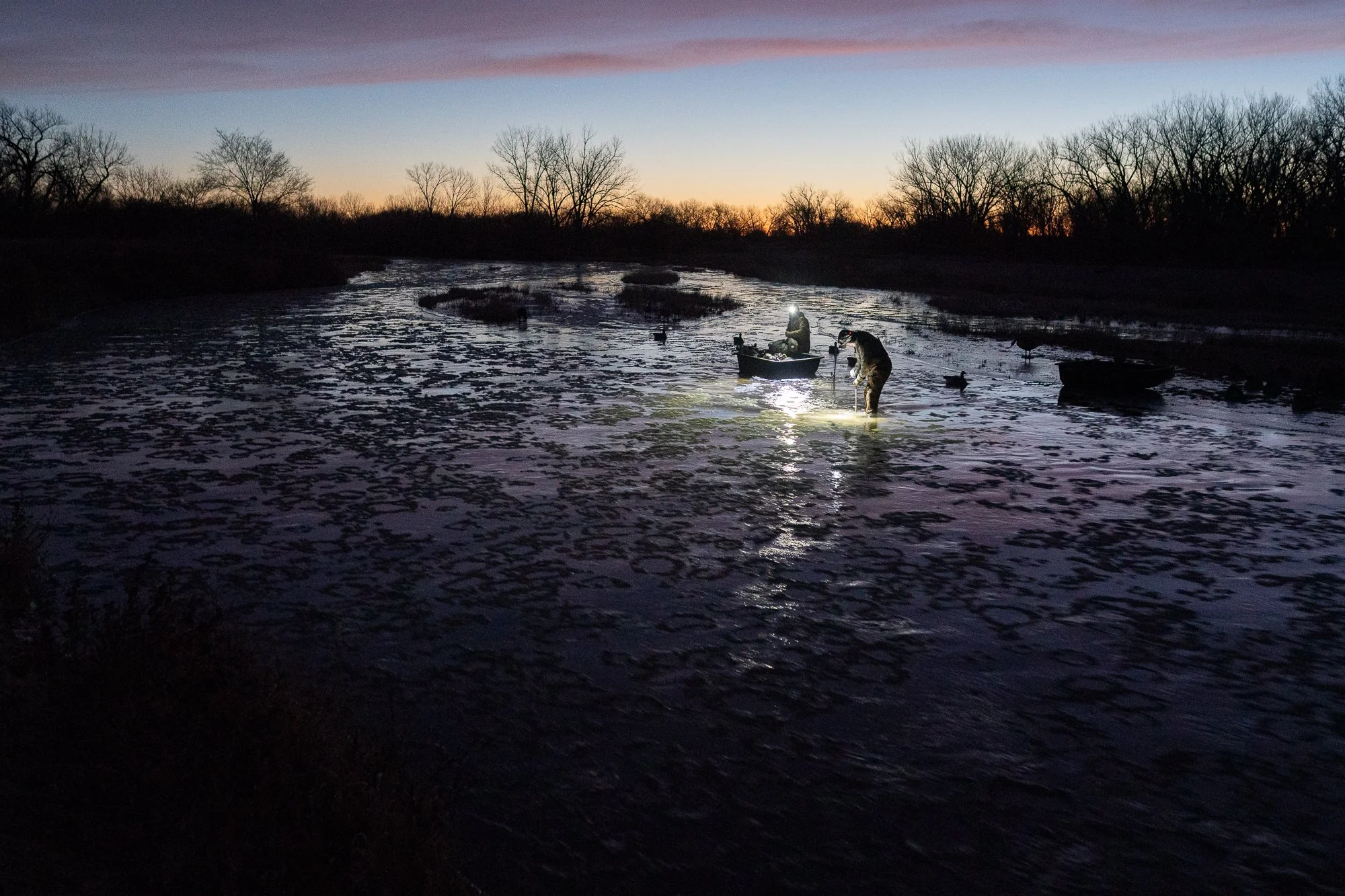 A duck blind glows from inside before dawn in the Nebraska marsh