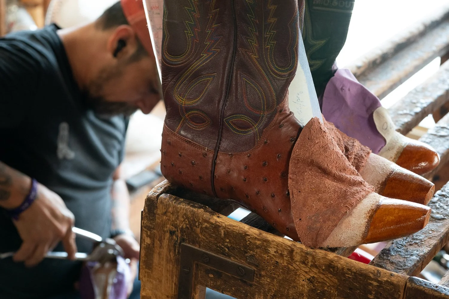Custom cowboy boots resting on a workbench during construction at ML Leddy’s