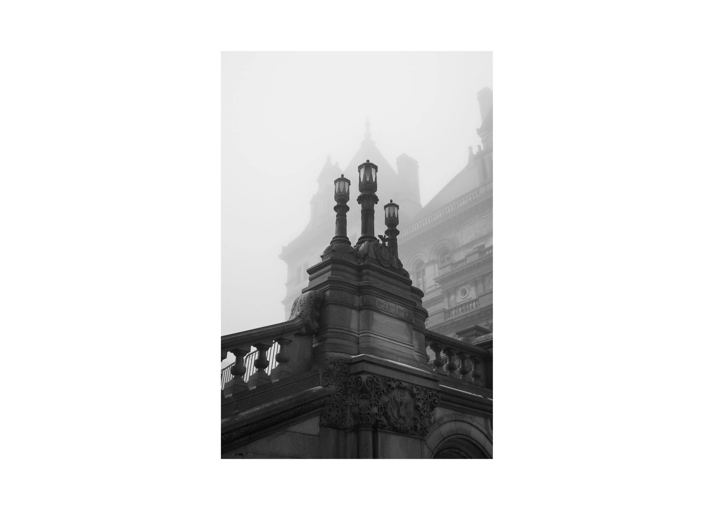 Black and white photograph of stone balustrades and ornamental lanterns at the New York State Capitol in Albany, New York, seen through winter fog