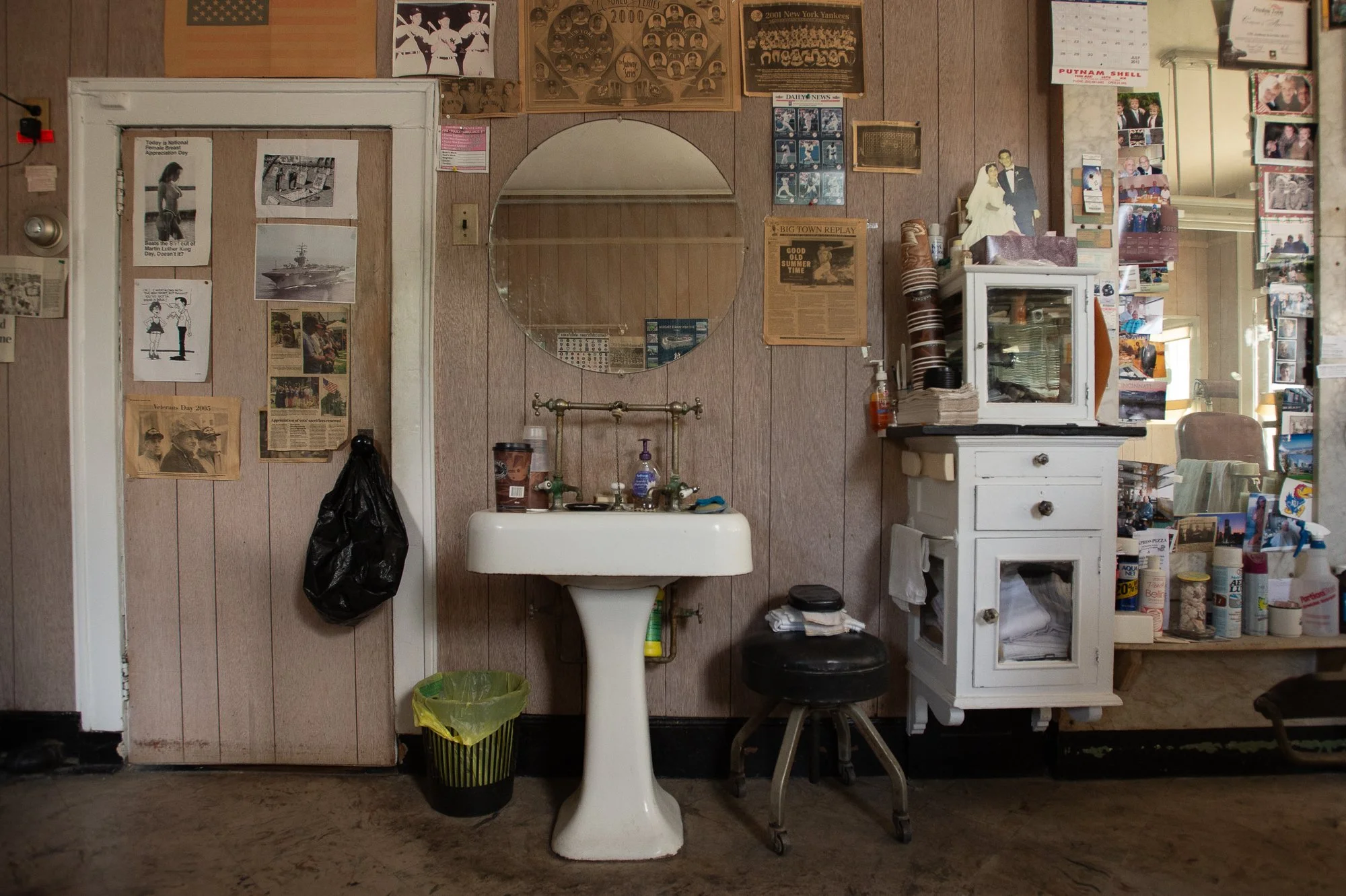 vintage sink and wall covered in photos inside Tony's Barbershop Greenwich Connecticut interior