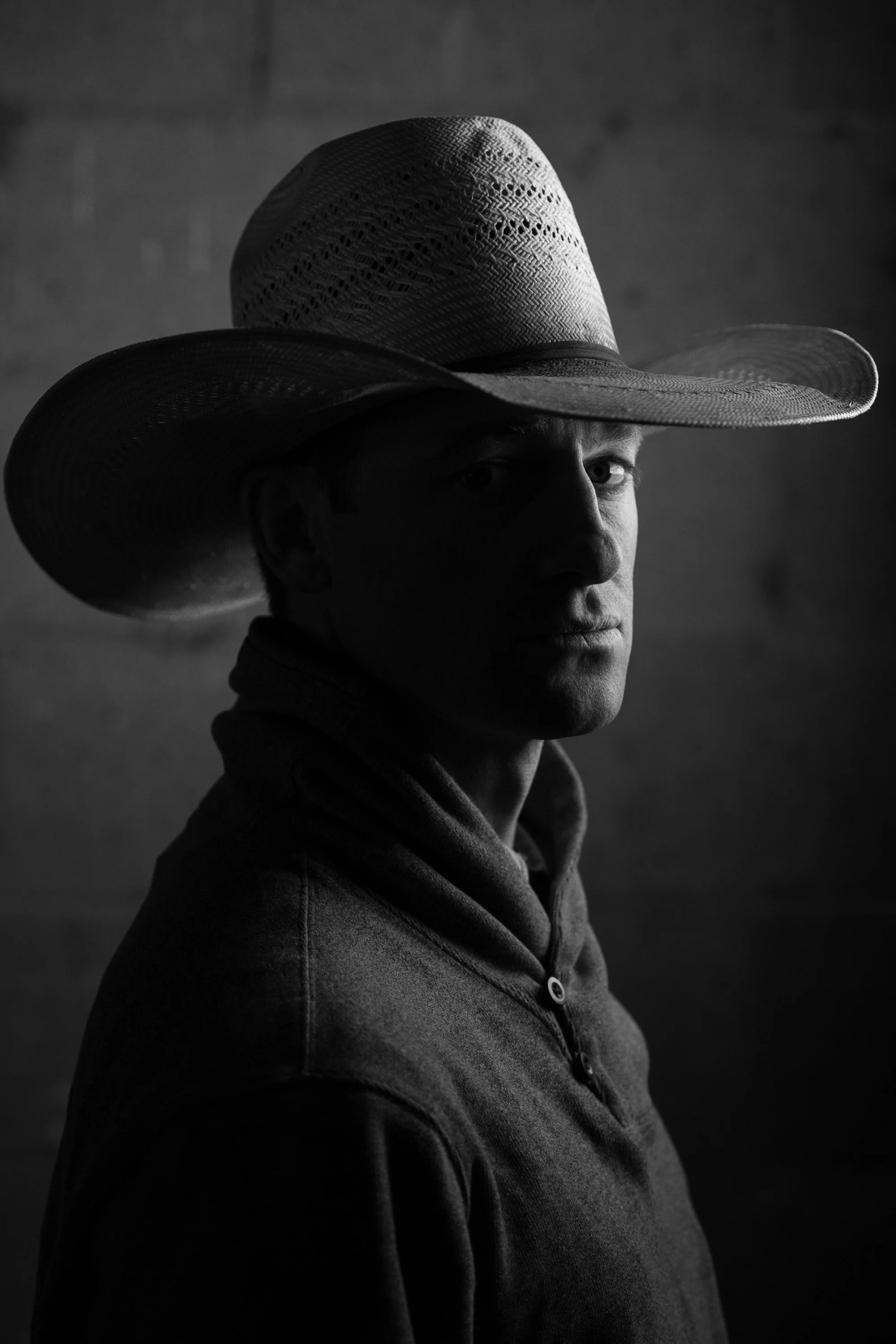 Black-and-white portrait of a cowboy wearing a wide-brimmed hat at Magnum Feedyard in Colorado