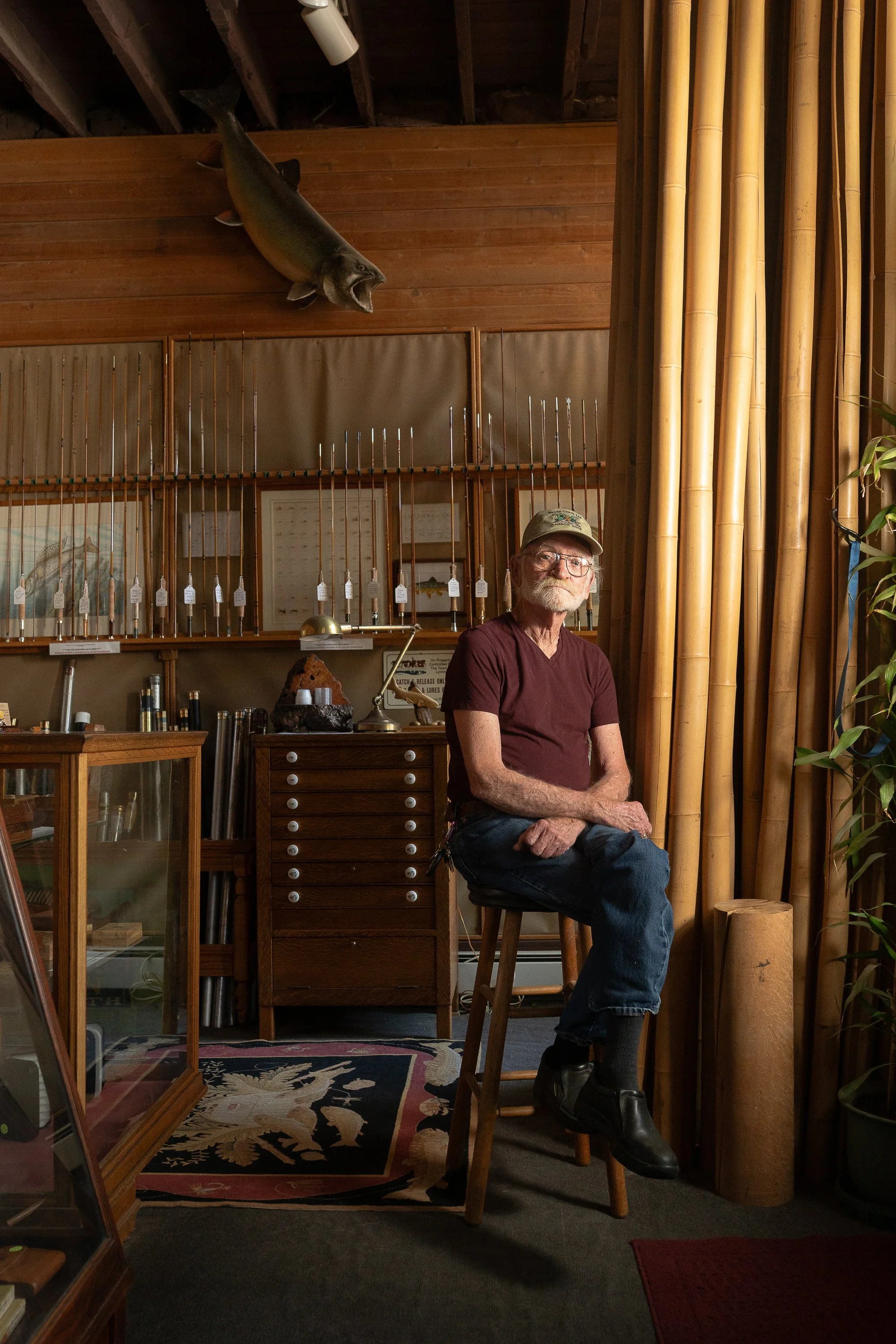 Mike Clark seated inside South Creek Ltd. beside bamboo cane and a collection of fly rods.