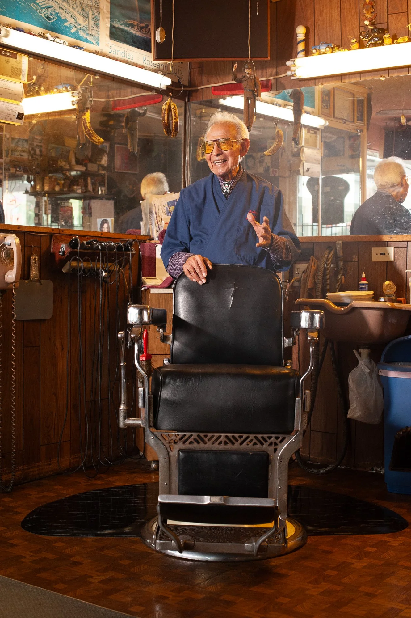 Portrait of a barber standing behind his chair in a traditional San Diego barbershop