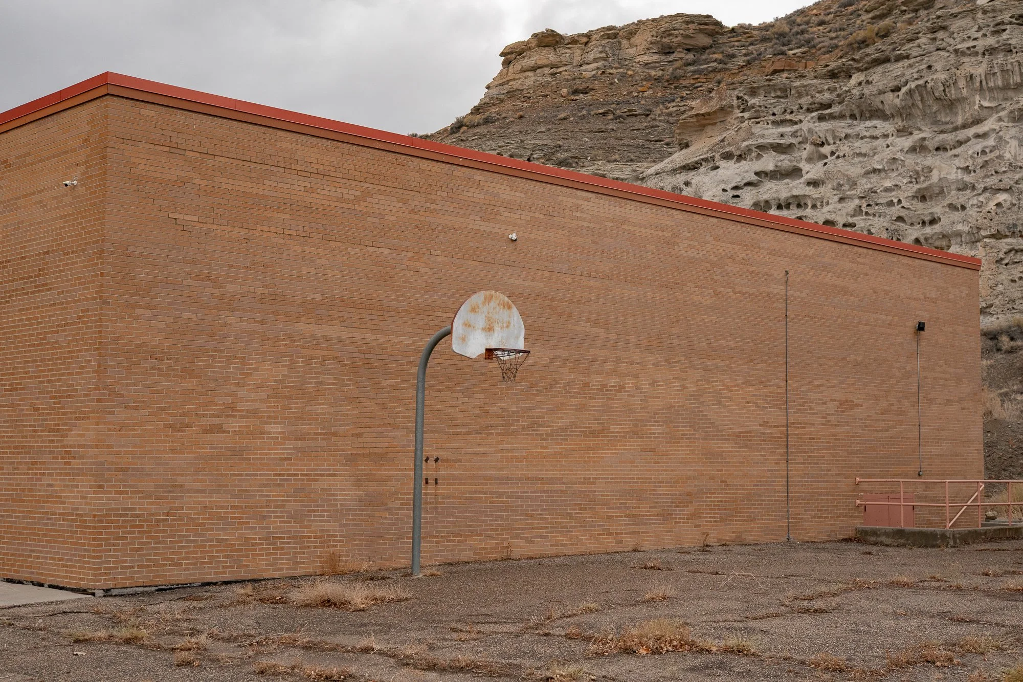 Basketball hoop mounted against a brick building beneath a Wyoming hillside