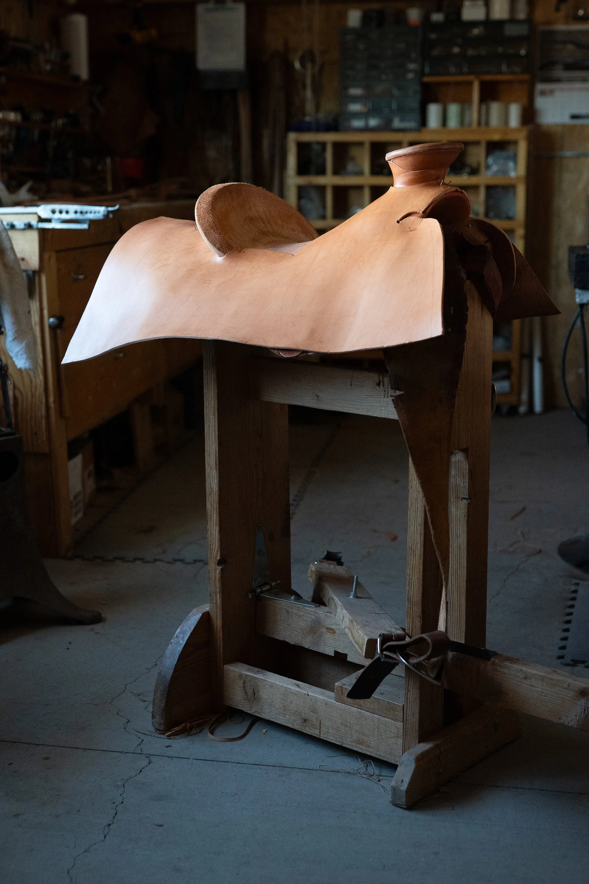Unfinished Mother Hubbard saddle covered with a broad piece of leather in Doug Cox's workshop.