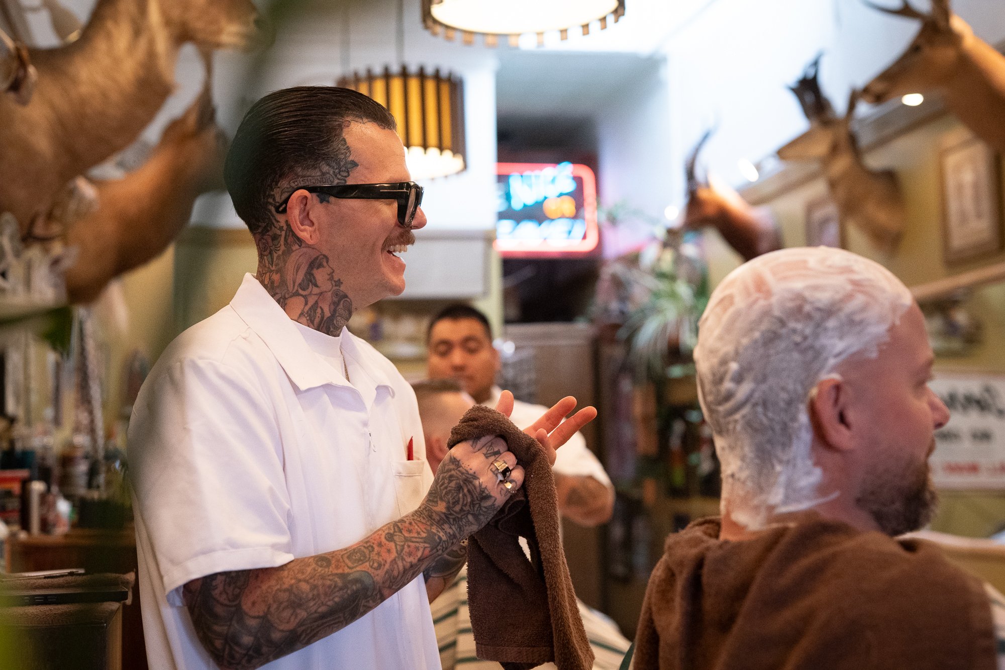 Barber holding a hot towel while working with a client during a grooming service inside the barbershop.