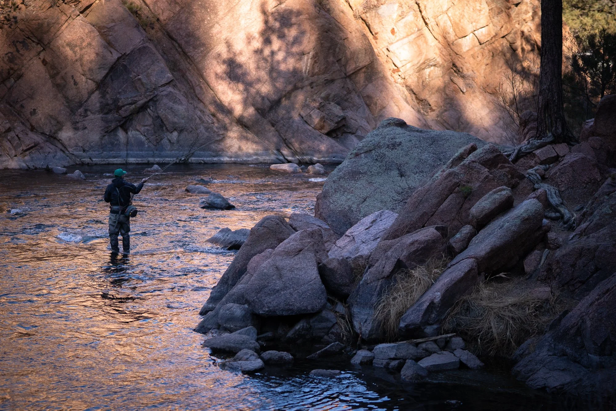 Angler fly fishing between large rocks on the South Platte River in Deckers Canyon