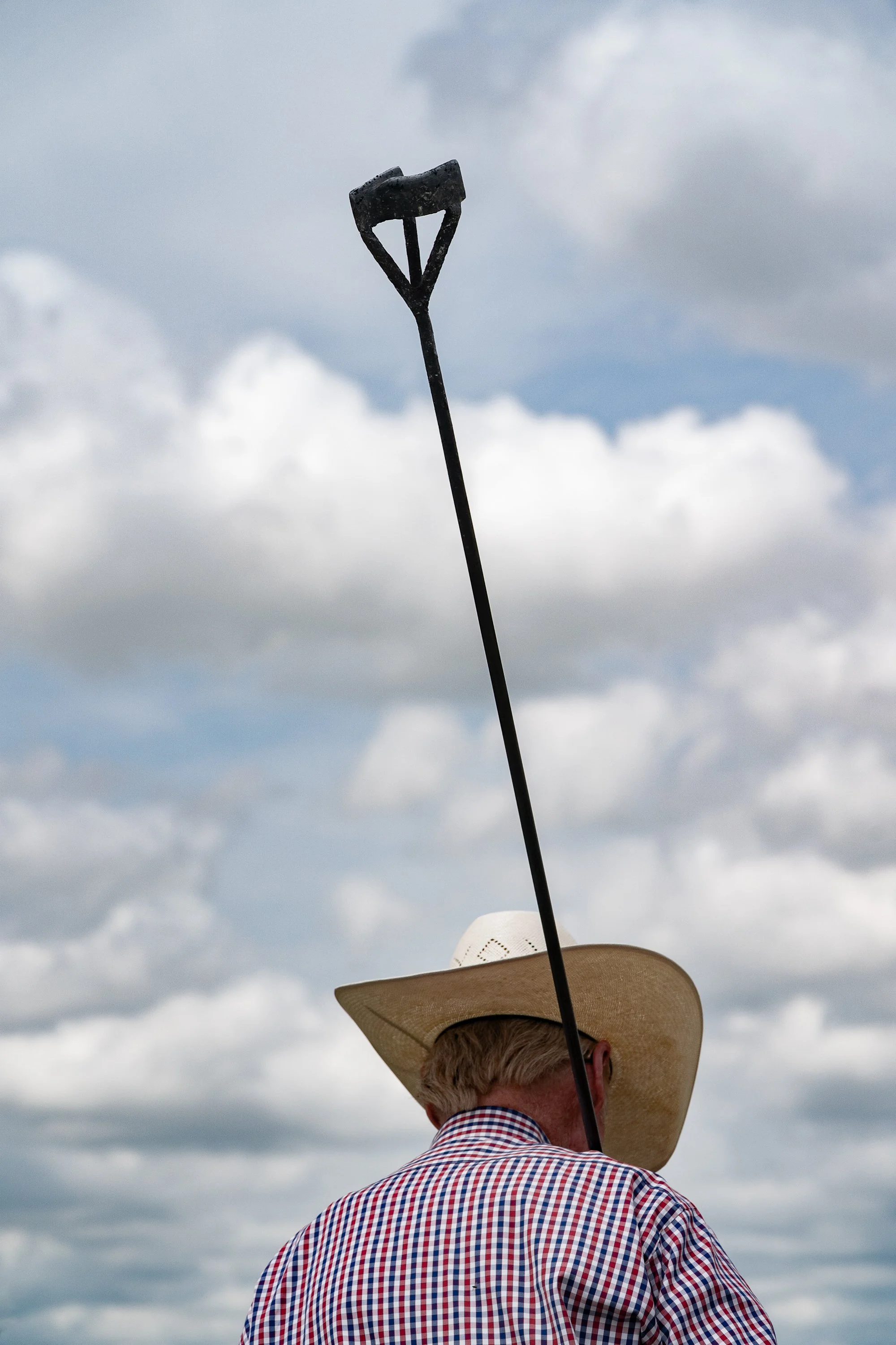Cowboy seen from behind holding a branding iron while standing in the Nebraska Sandhills at Haythorn Ranch.