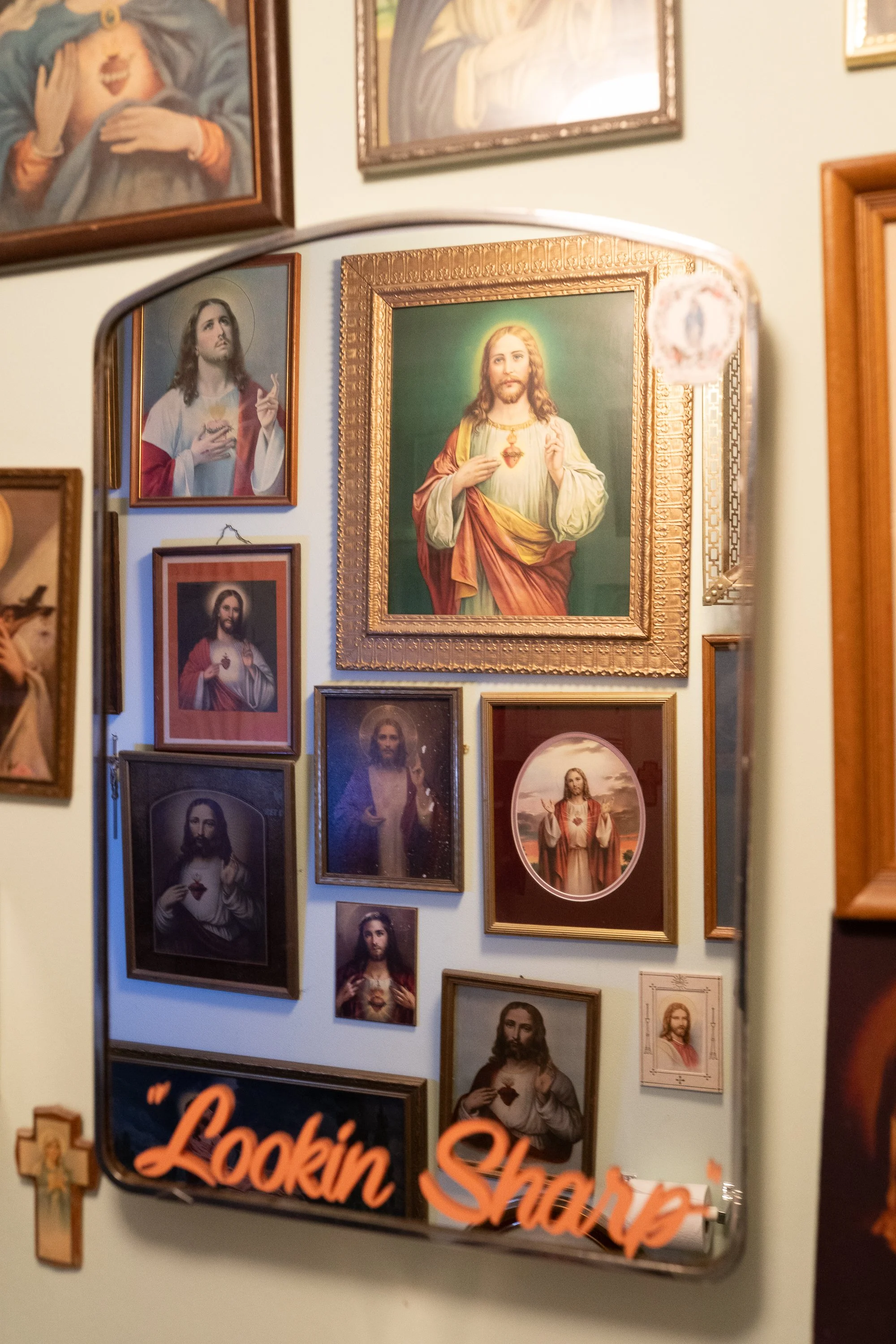 Religious artwork and framed Sacred Heart images displayed on the wall inside Spanky’s Barbershop in Covington, Kentucky.