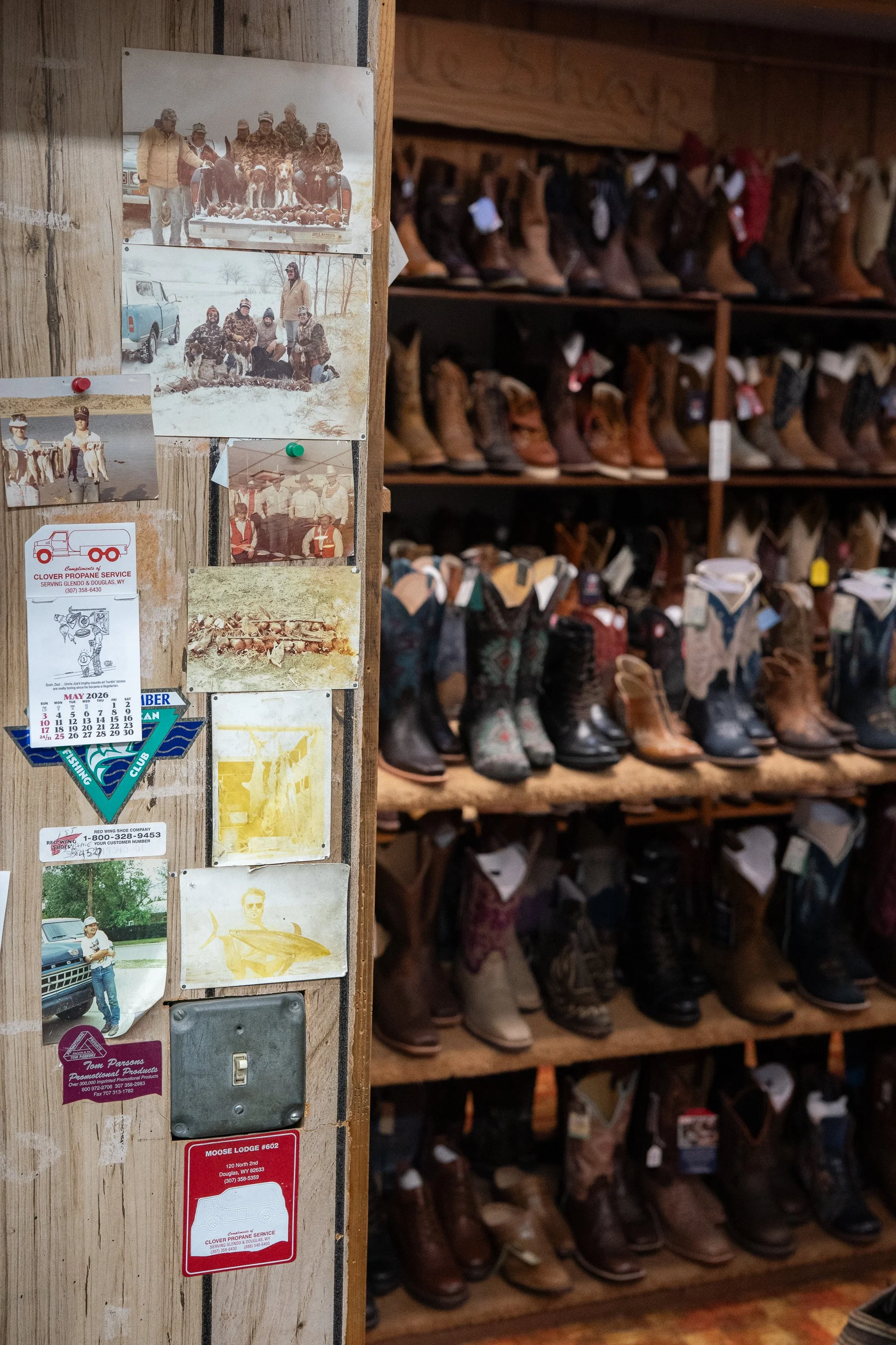 Rows of Western boots on wooden shelves beside pinned photographs, calendars and local memorabilia at City Shoe & Saddle Shop in Douglas, Wyoming.