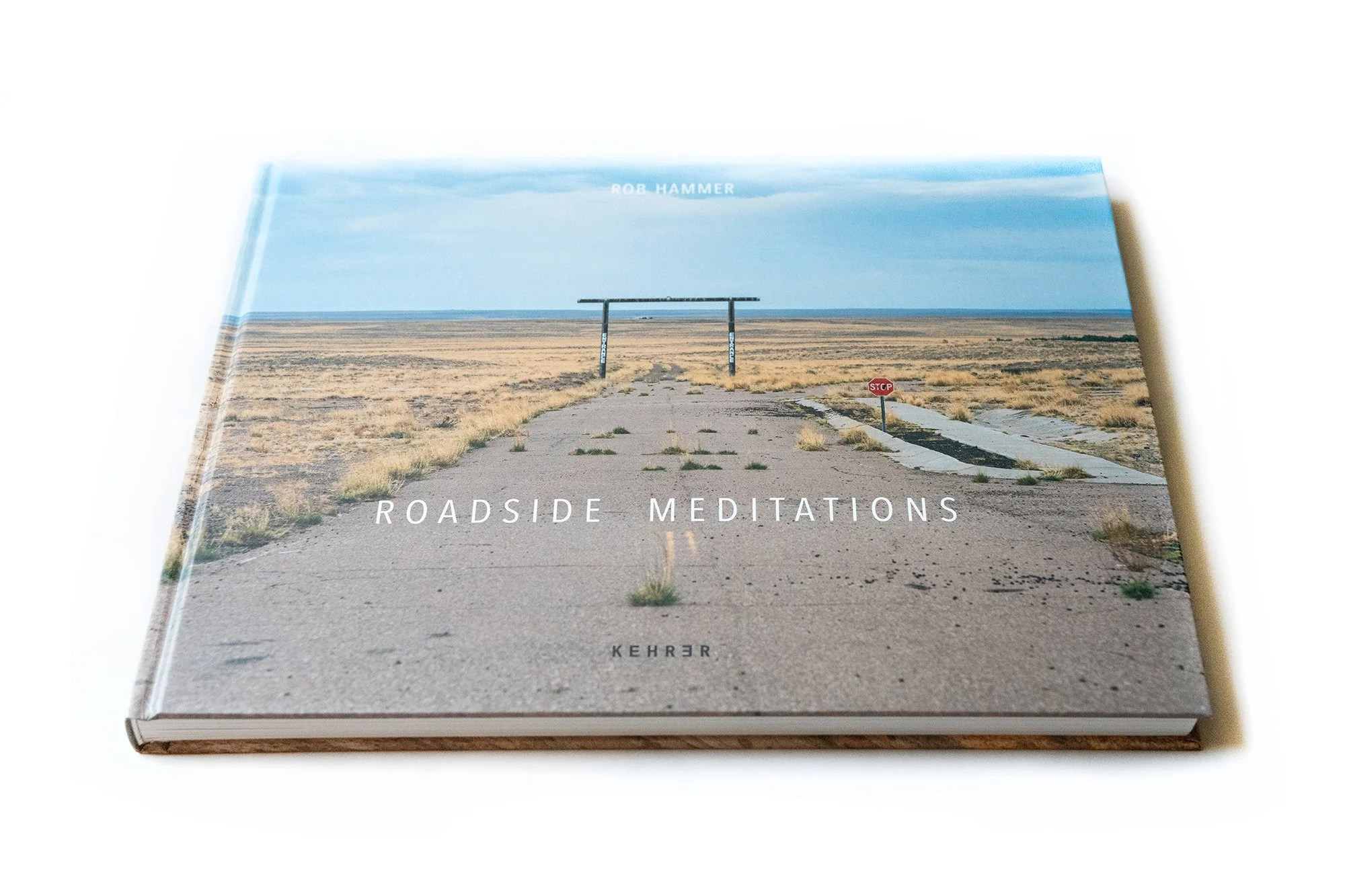 Roadside Meditations photography book cover featuring empty desert road and intersection in the American West