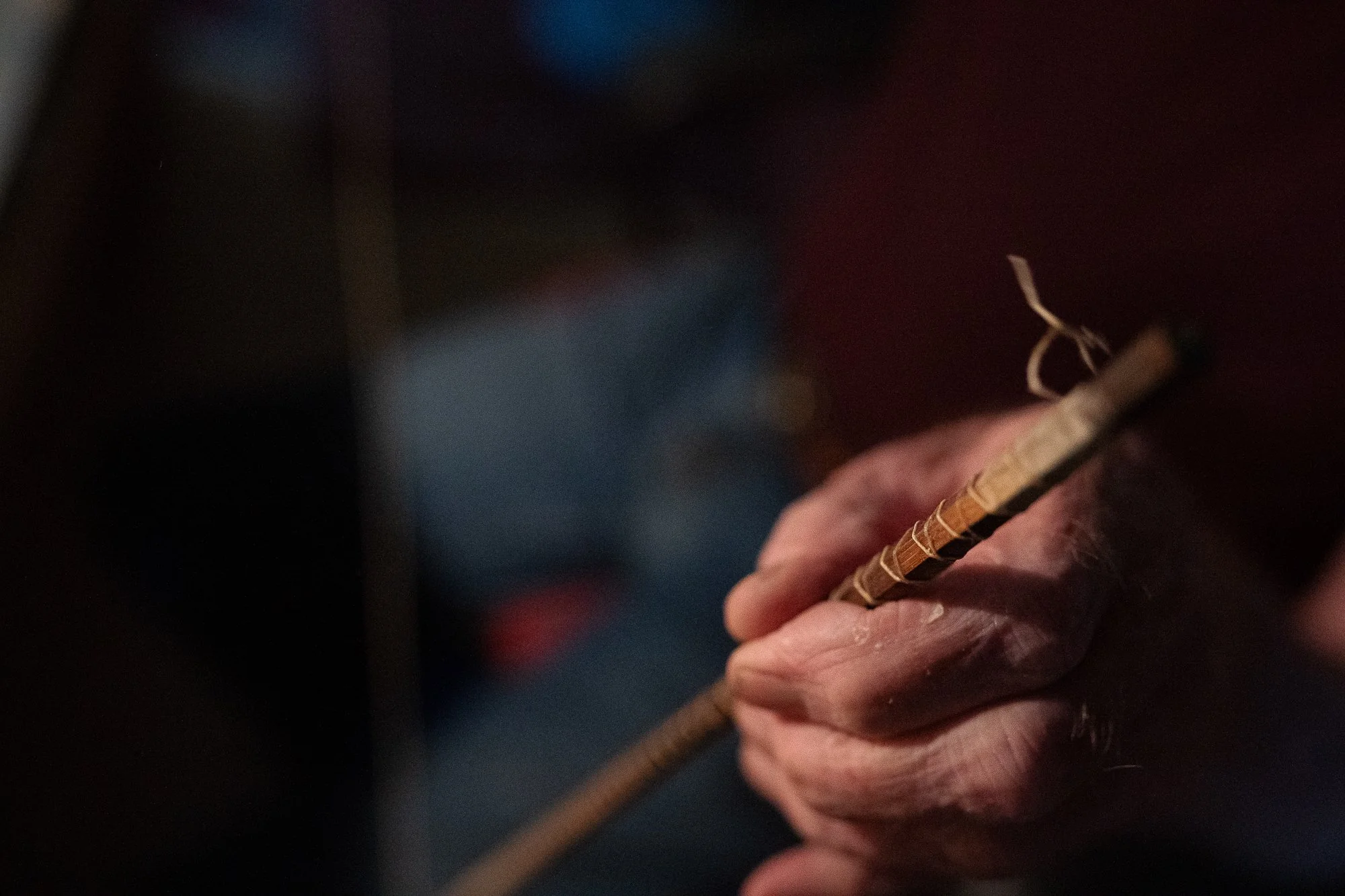 Close-up of Mike Clark's hands holding a bound section of bamboo fly rod.