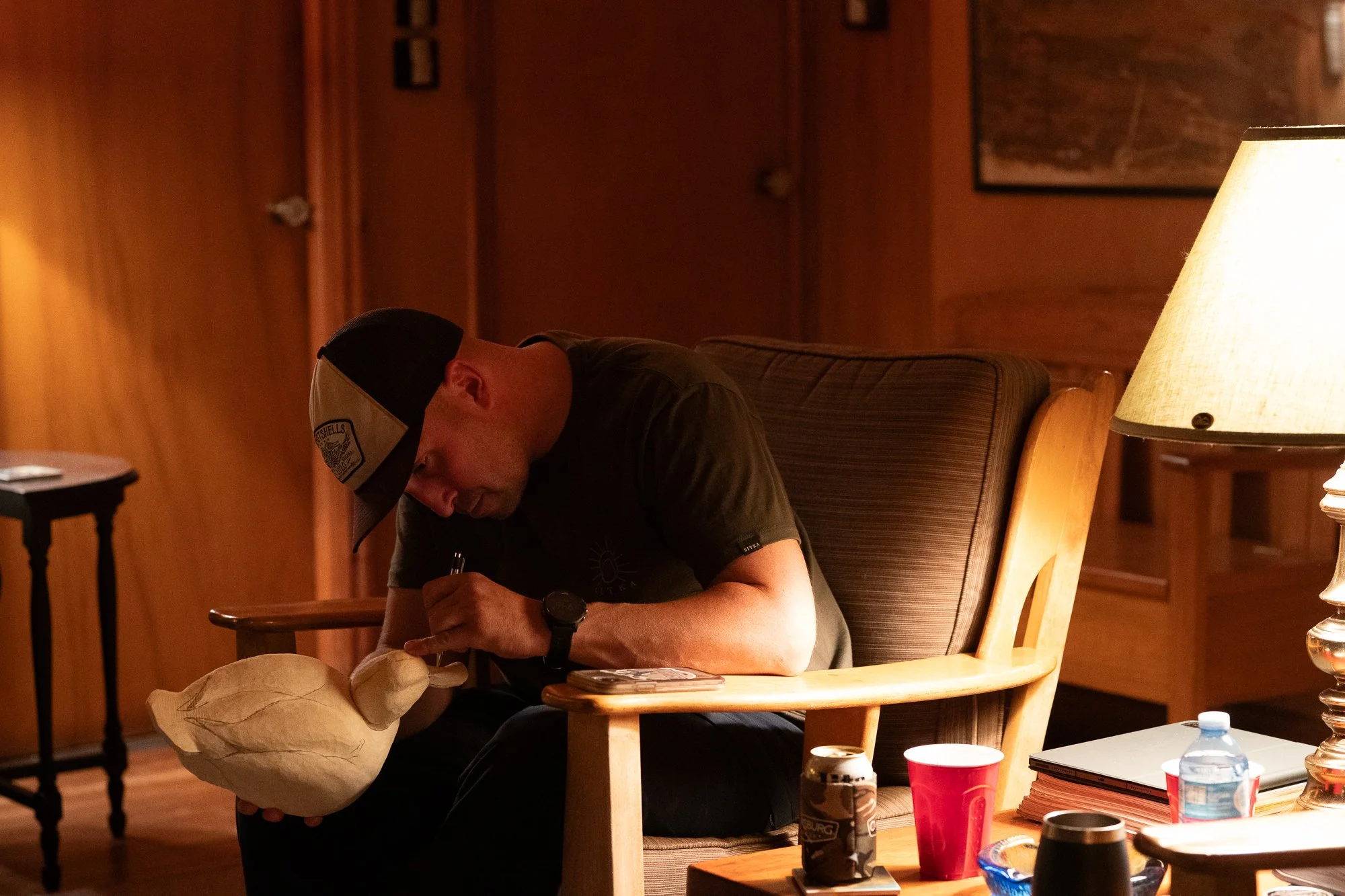 A hunter carves a duck decoy inside a lodge after a day in the marsh