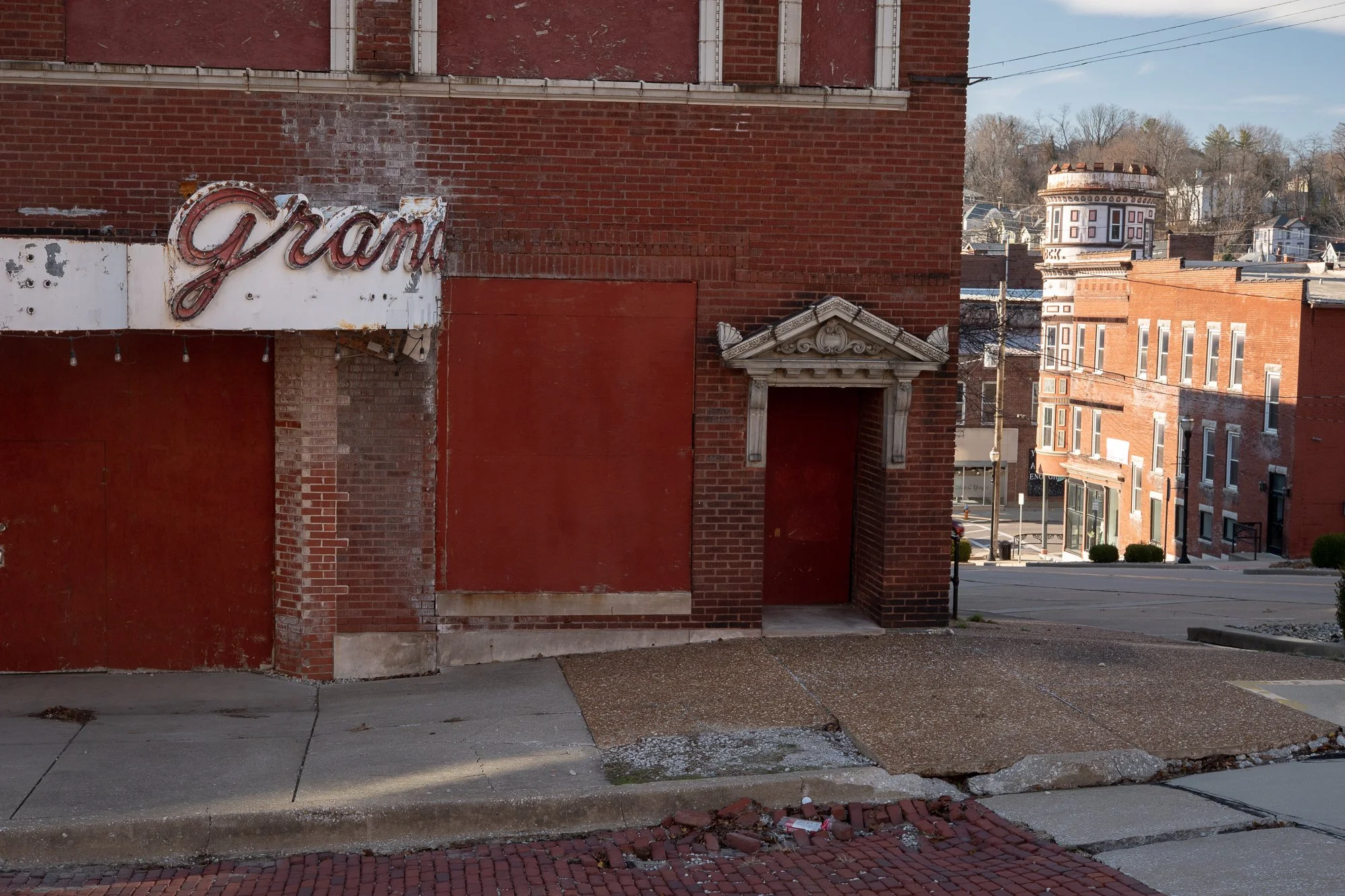 Faded painted lettering on a red brick building with boarded windows in Alton, Illinois