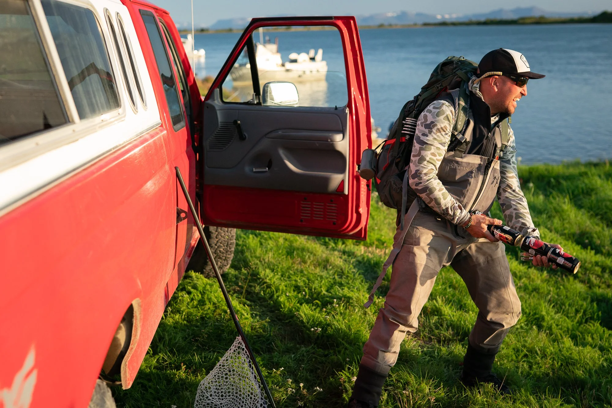 Fly fisherman carrying fishing gear beside a truck near an Alaskan lake