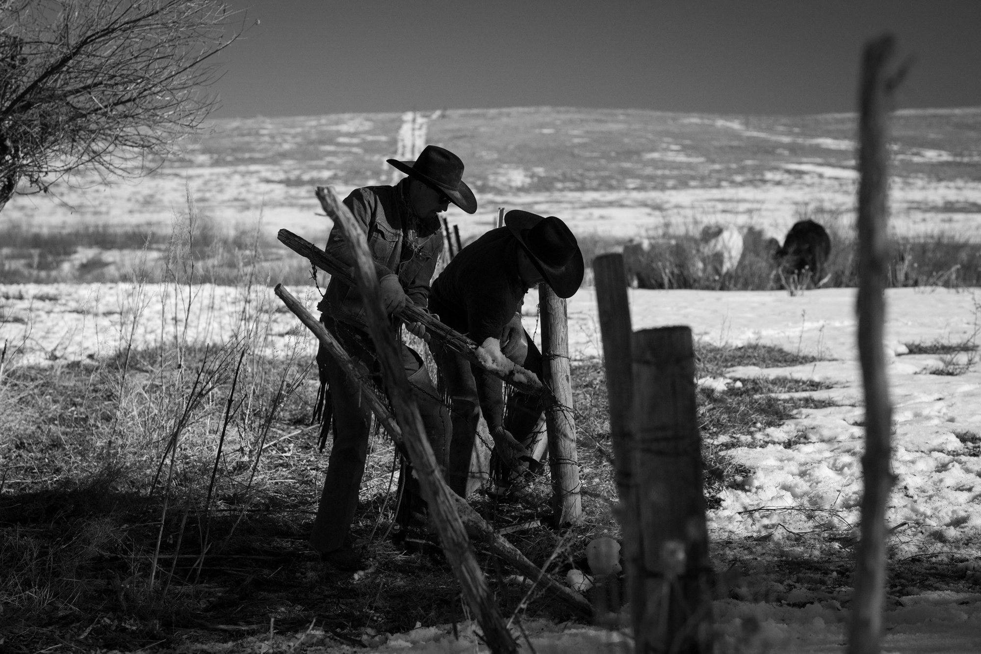 Two ranch hands repair a fence in the snow at Silver Spur Ranch in Colorado