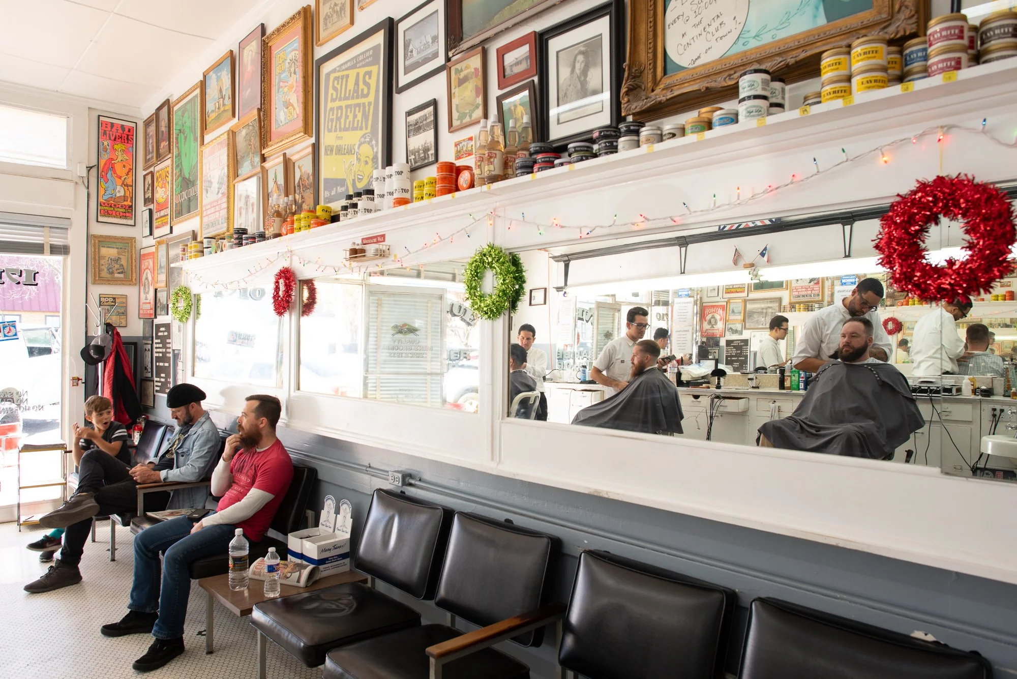 Customers sit along the wall in the waiting area inside Avenue Barbershop in Austin, Texas