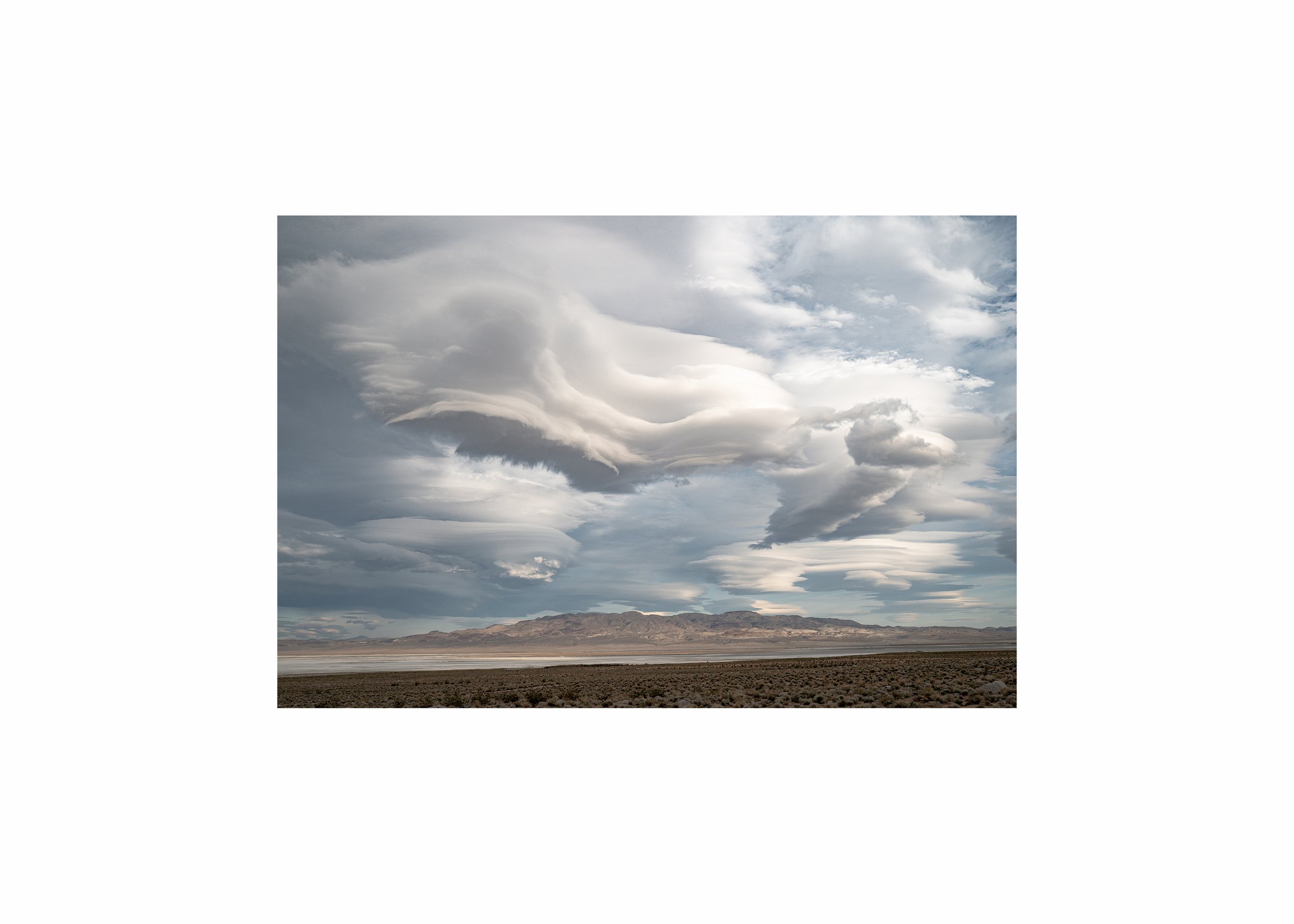 A dramatic, multi-layered lenticular cloud formation over a desert mountain range.