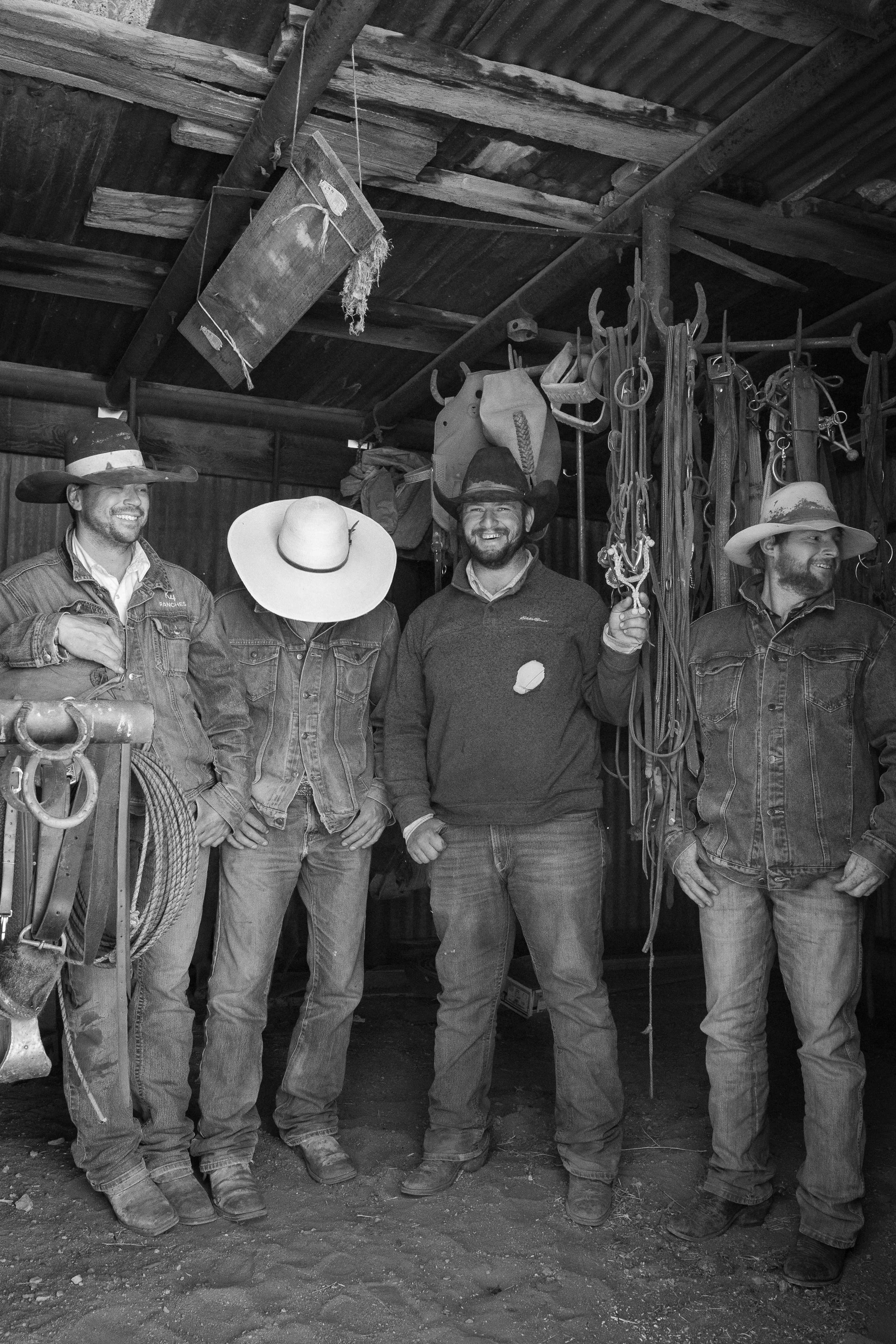 Working cowboys standing in a tack room with ropes and saddles at the Diamond A Ranch in Arizona