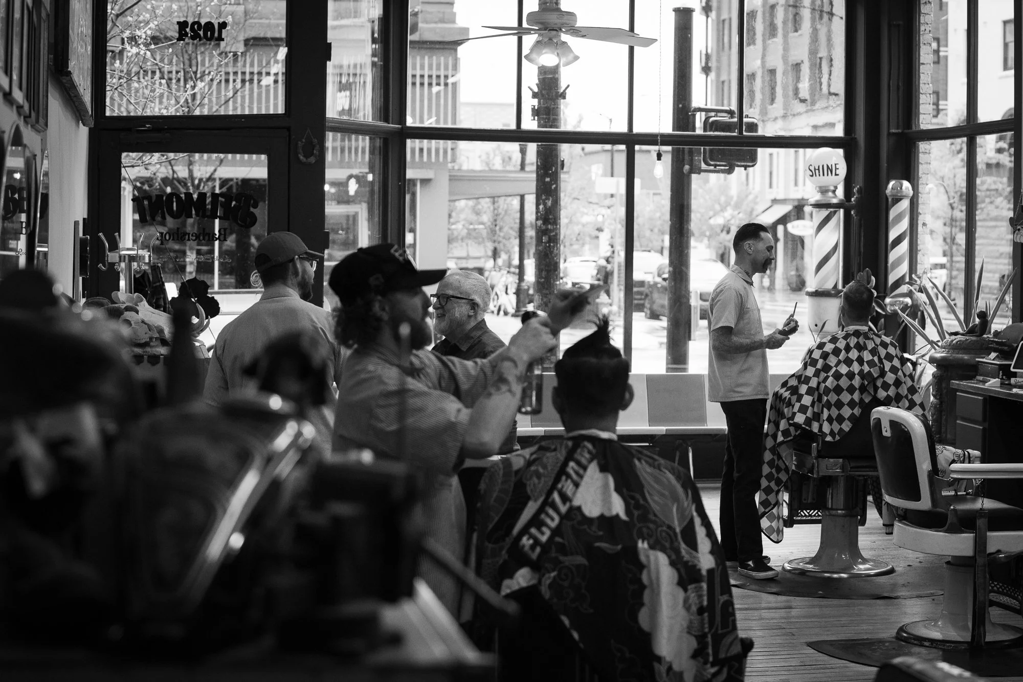 busy interior of Belmont Barbershop in Boise Idaho with barbers cutting hair and clients seated