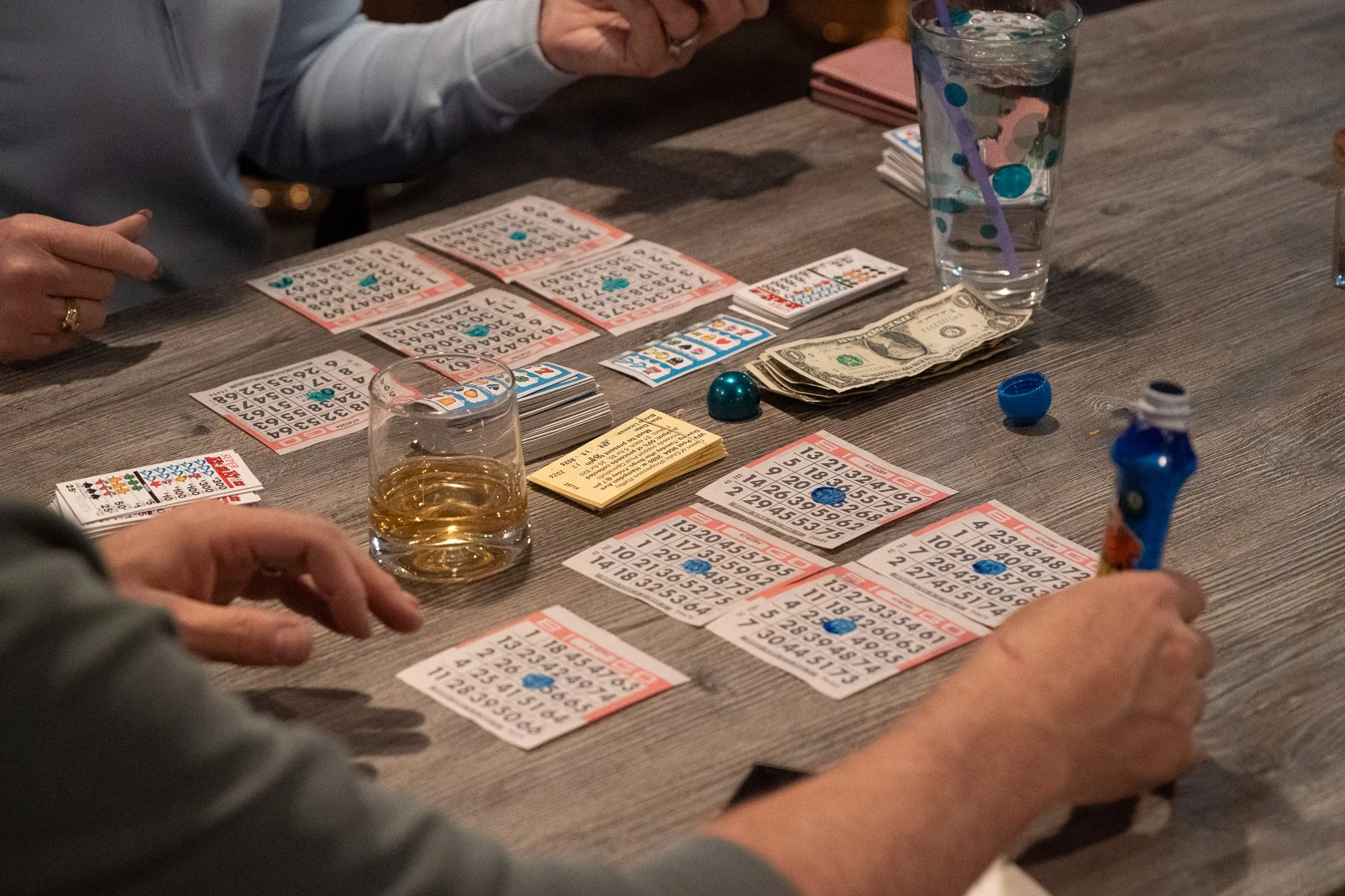 Bingo cards, drinks, and cash on a table inside a VFW hall