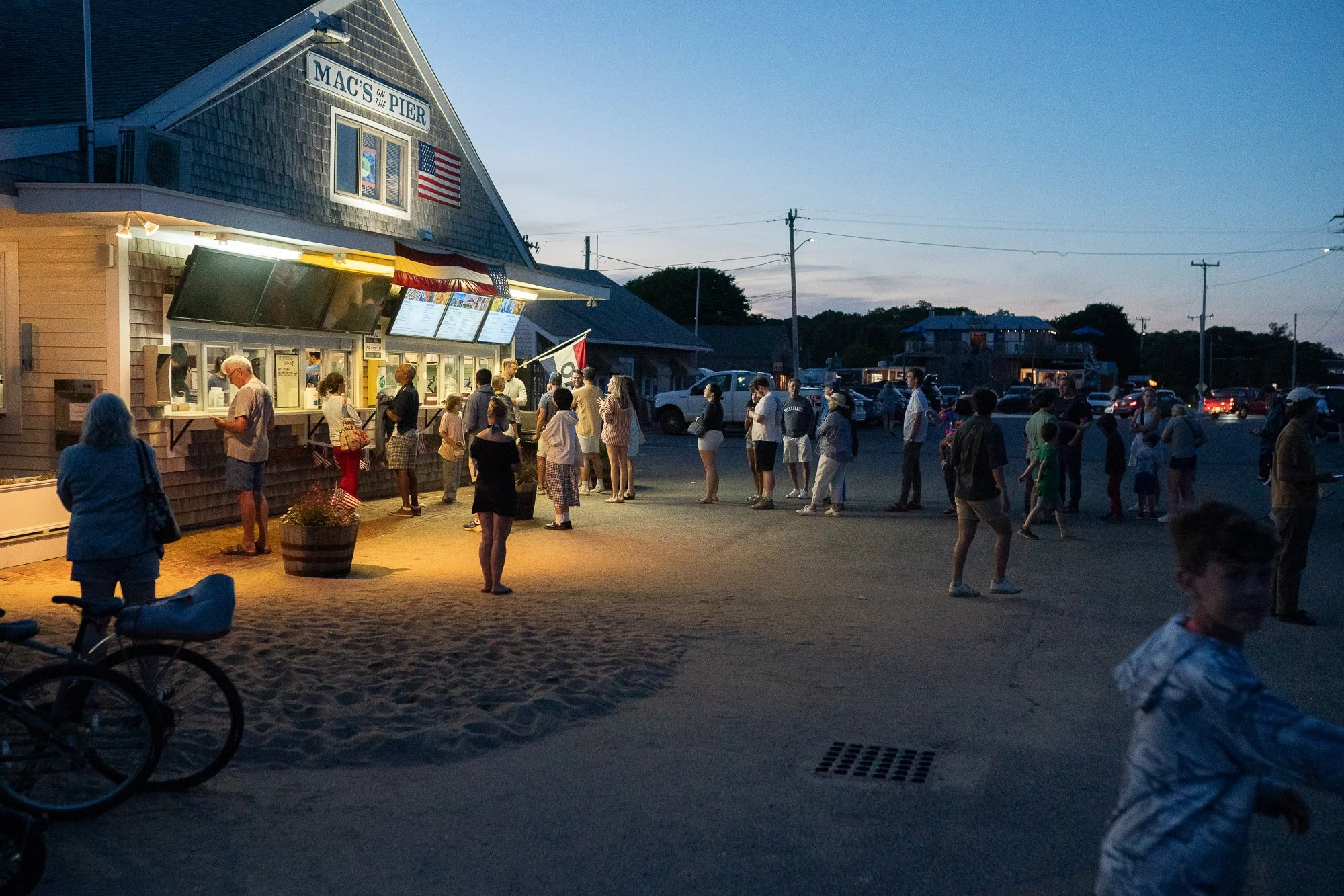 Evening scene at Mac’s on the Pier in Wellfleet with people lined up for seafood under soft light
