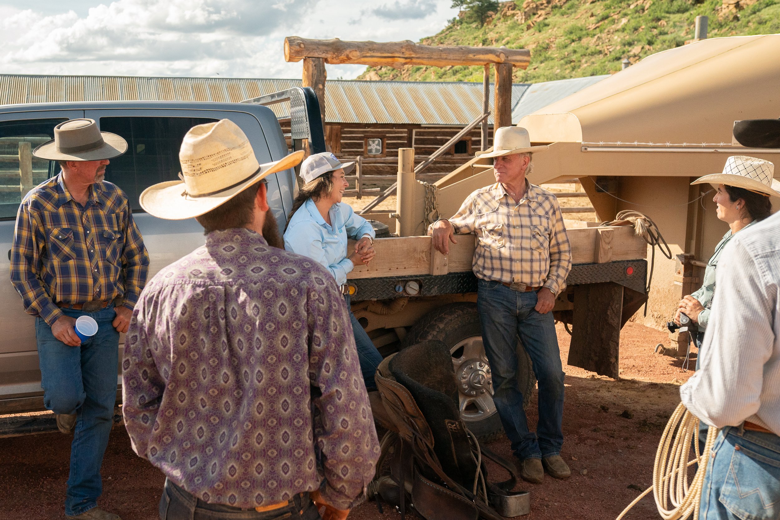 Group of cowboys standing and leaning around a ranch truck talking after work in Montana