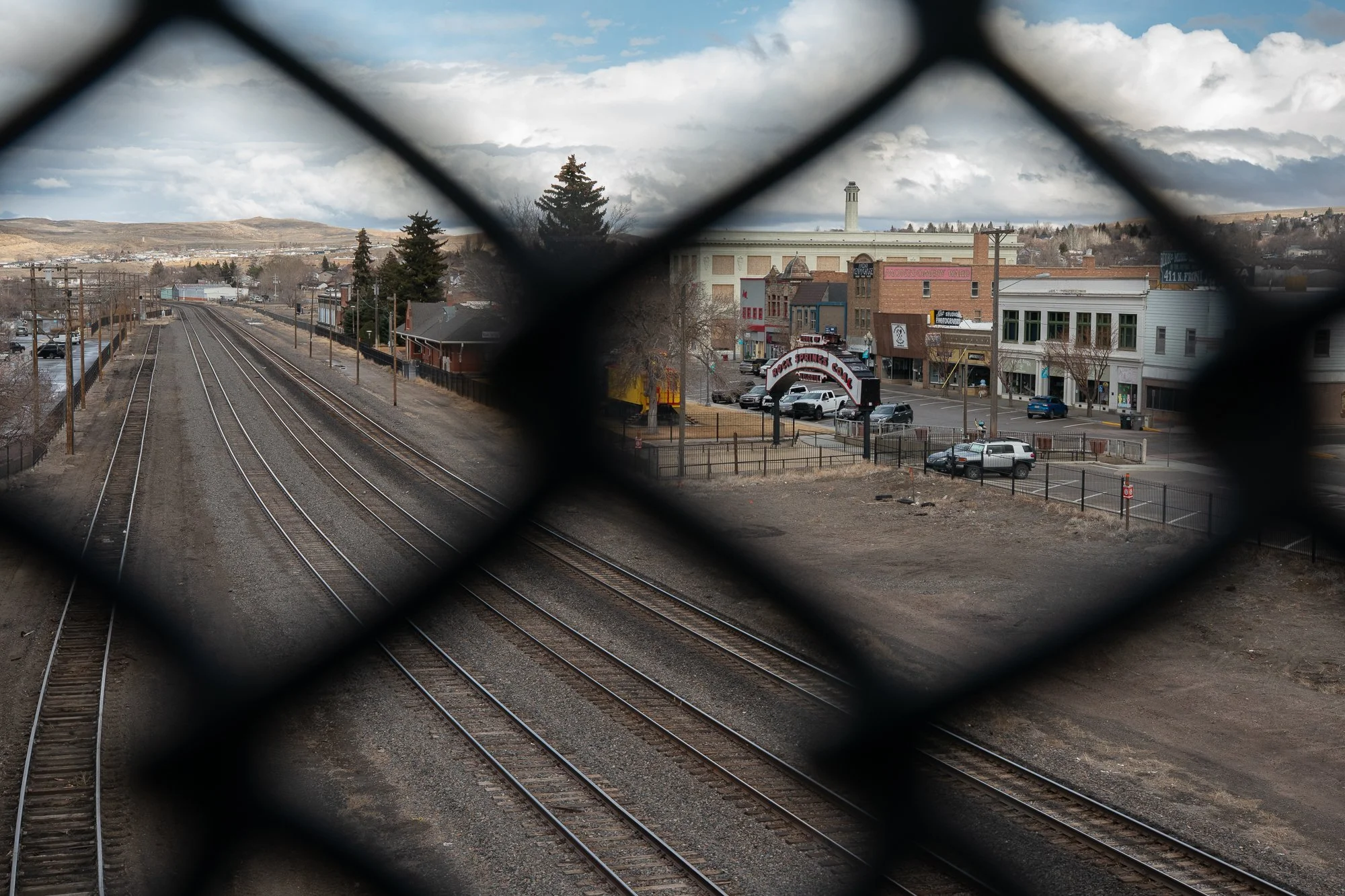 Railroad tracks leading toward downtown Rock Springs Wyoming seen through chain link fence