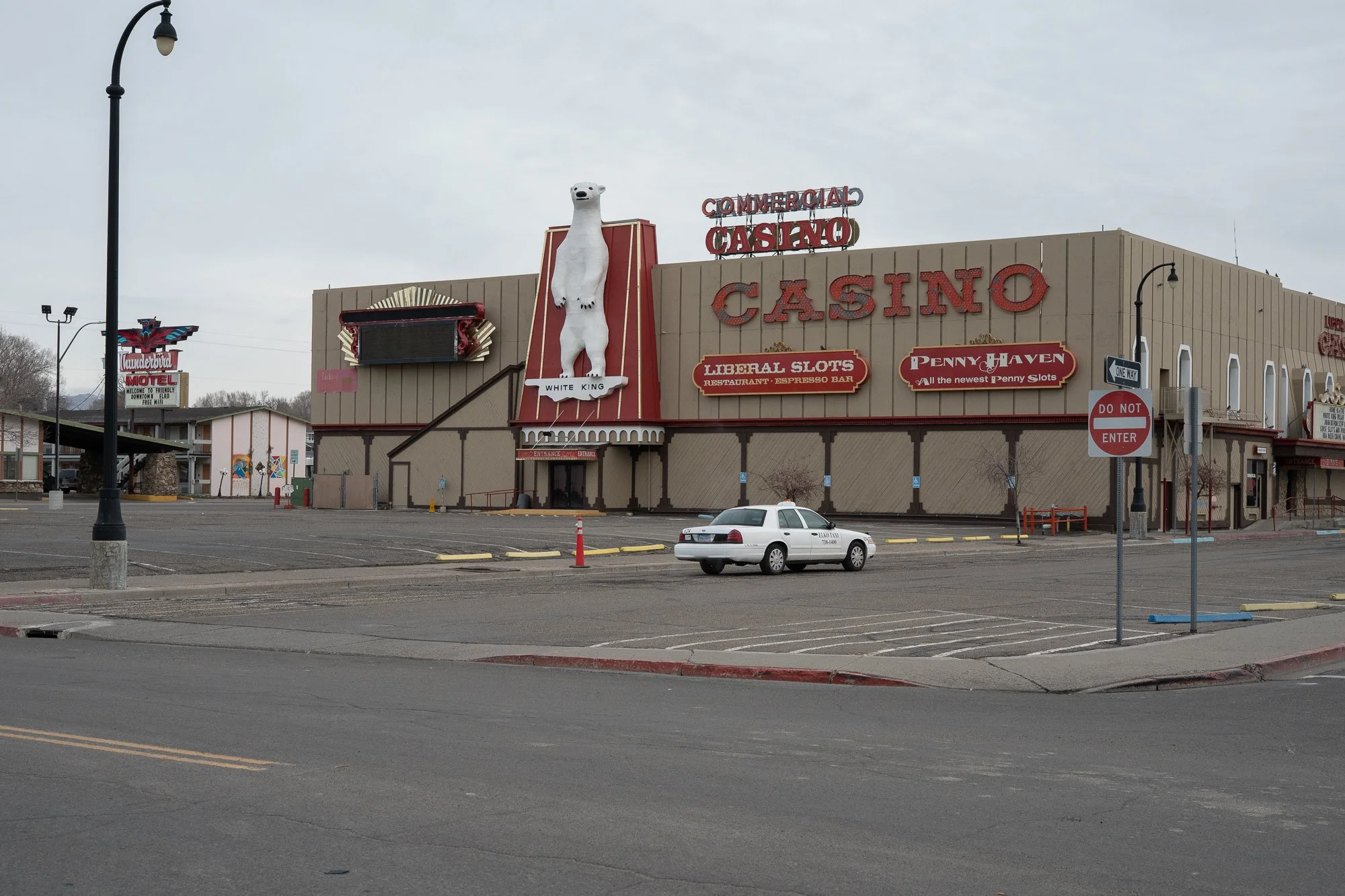 Exterior of the Commercial Casino in Elko, Nevada, with a large white polar bear sculpture on the facade and a lone taxi in an empty parking lot.