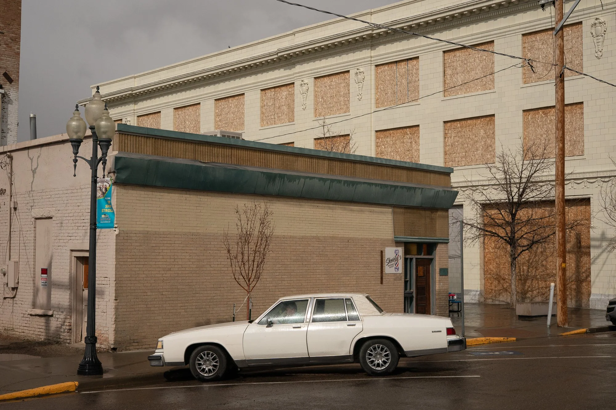 Older sedan parked beside buildings with boarded windows in downtown Rock Springs Wyoming
