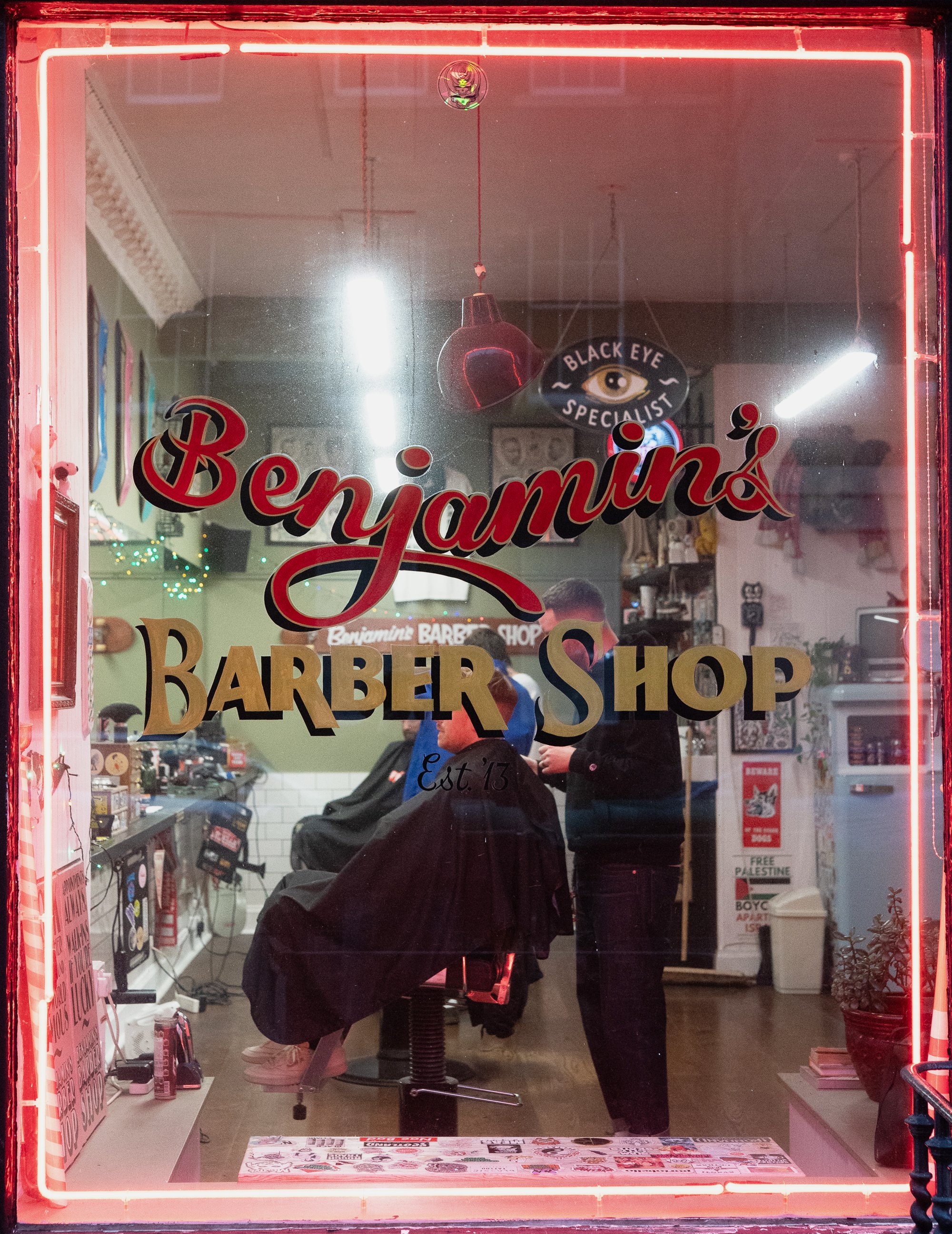 barber cutting hair inside benjamins barber shop edinburgh through window