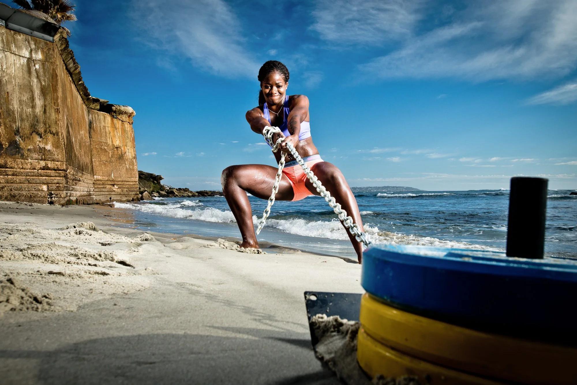 Fitness athlete training on beach with sled resistance workout ocean