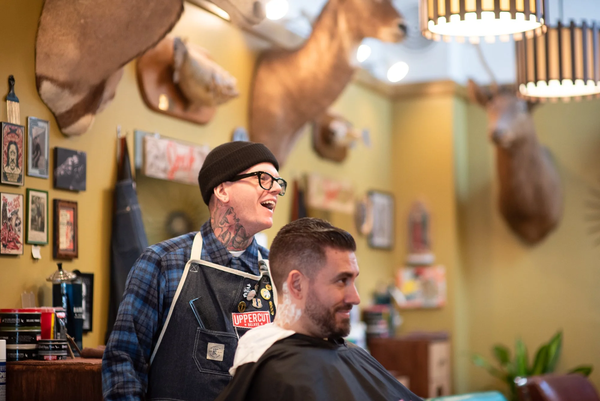 Pugsly shares a laugh with a client during a haircut at his barbershop in Kingston, New York.