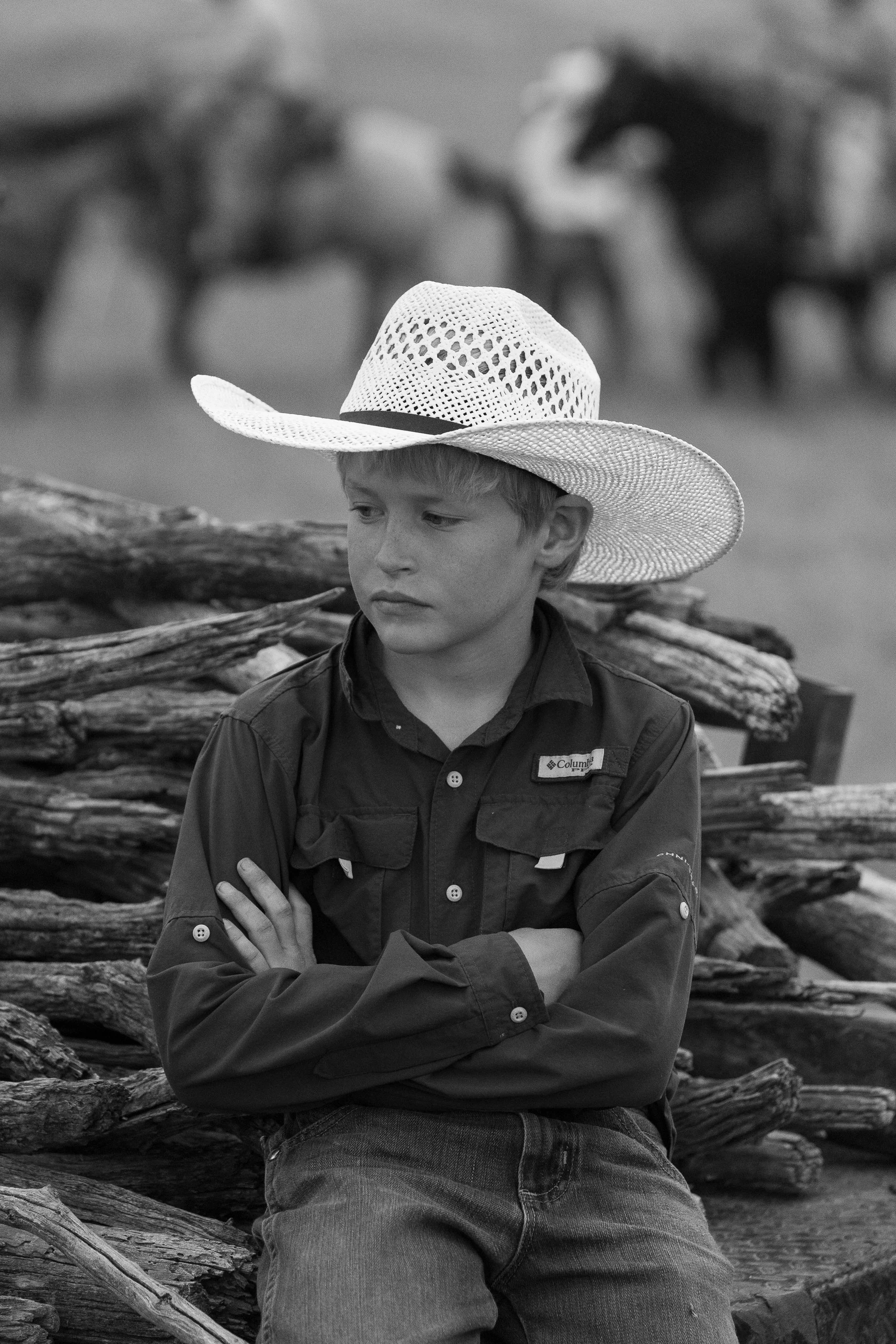 Young boy wearing a cowboy hat watching ranch work during a branding day at Haythorn Ranch.
