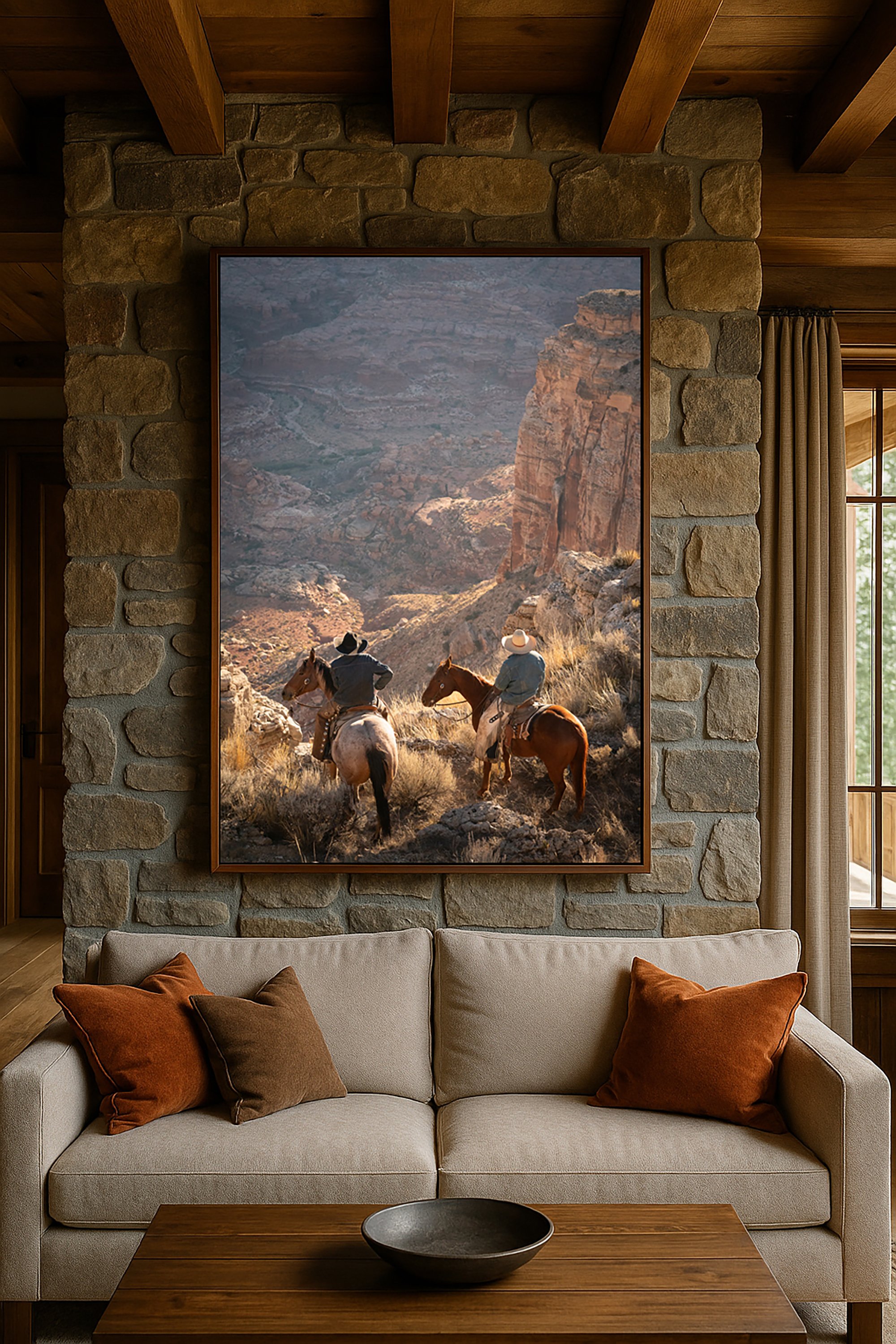 Large framed Western photography print of riders in canyon country displayed above a living room sofa
