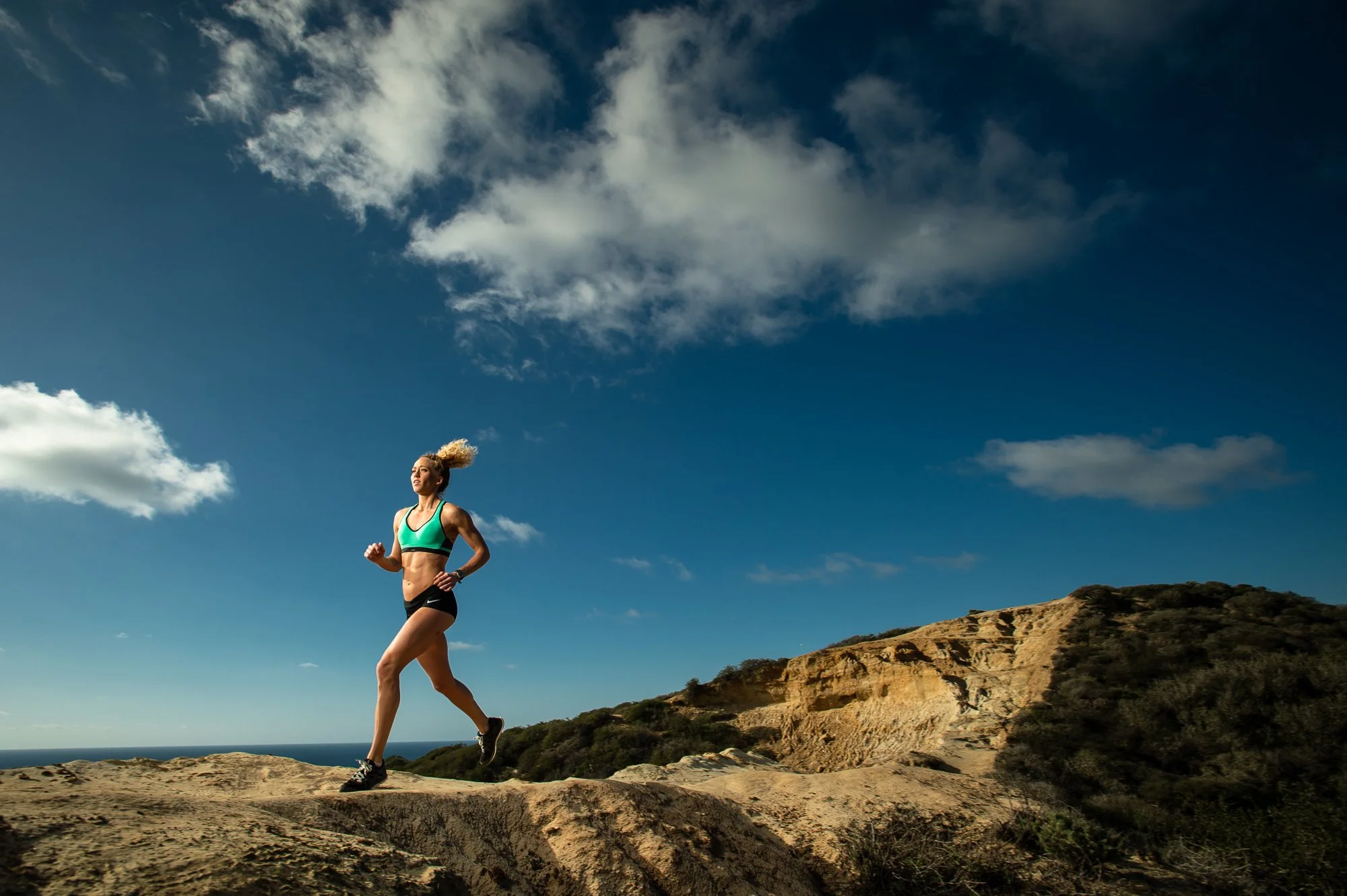 Female runner on open landscape with blue sky fitness workout