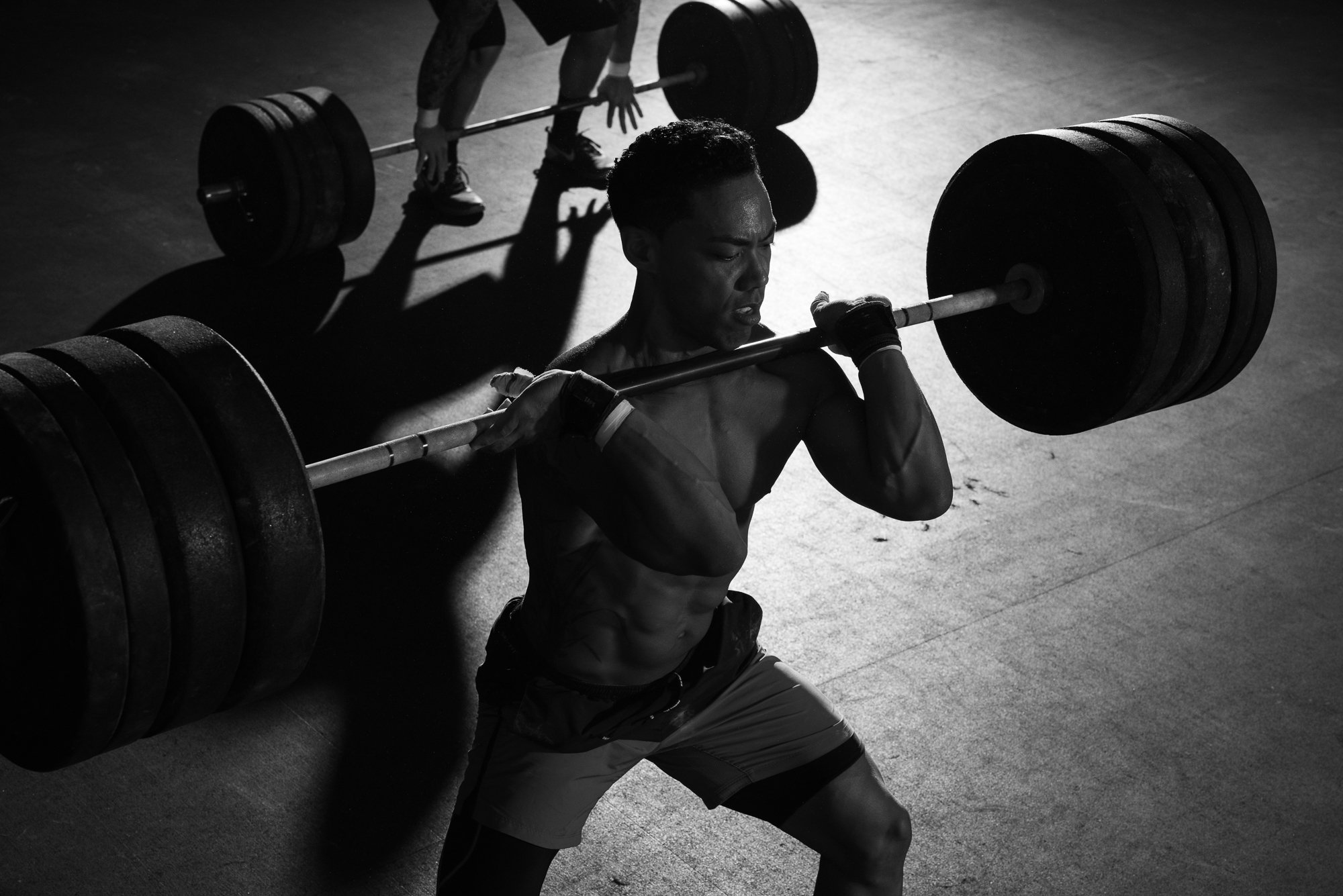 CrossFit athlete driving upward from a deep squat with a heavily loaded barbell in the front rack position.