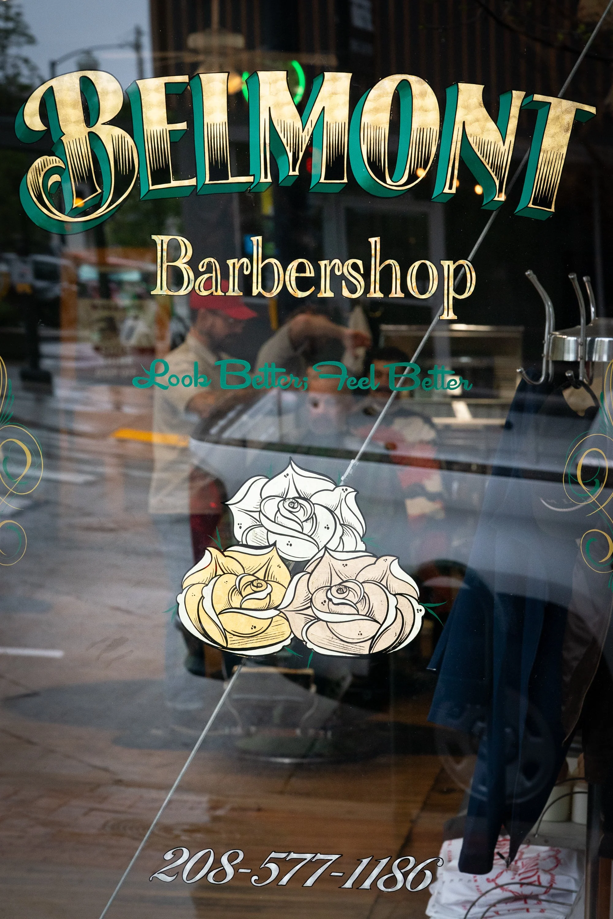 Belmont Barbershop window sign in Boise Idaho with barbers reflected inside