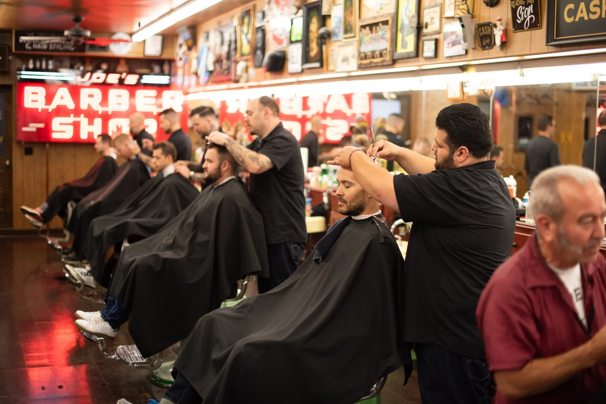 Barbers cutting hair along the mirror wall at Joe’s Barbershop in Chicago