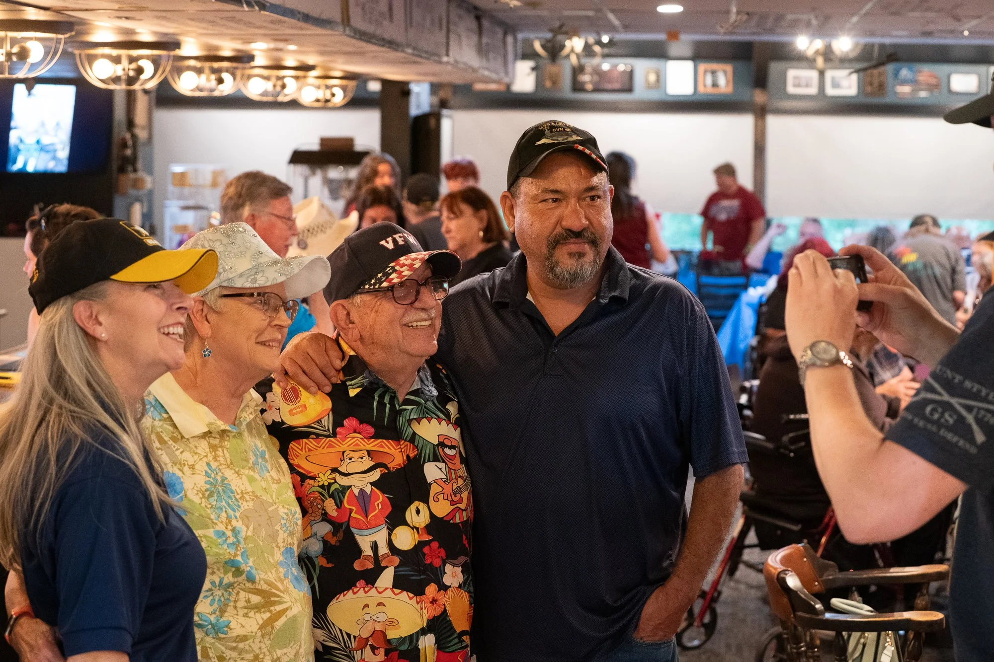 Group posing for a photo inside a VFW hall during a veterans brand campaign