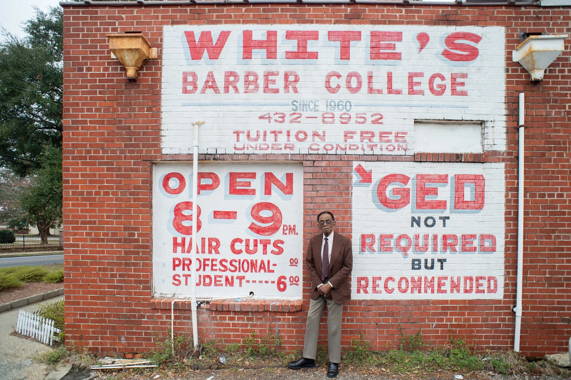 Man standing in front of Whites Barber College exterior with painted signage