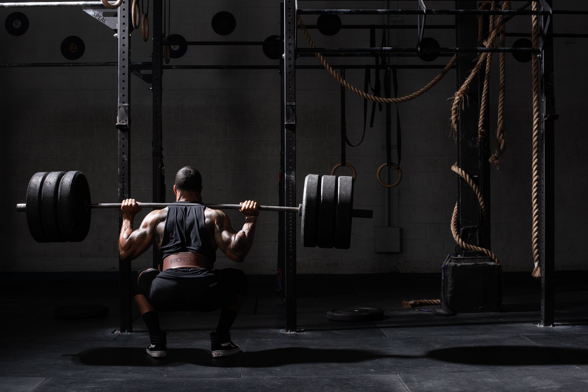 Athlete performs a heavy back squat with a loaded barbell in a Colorado training gym