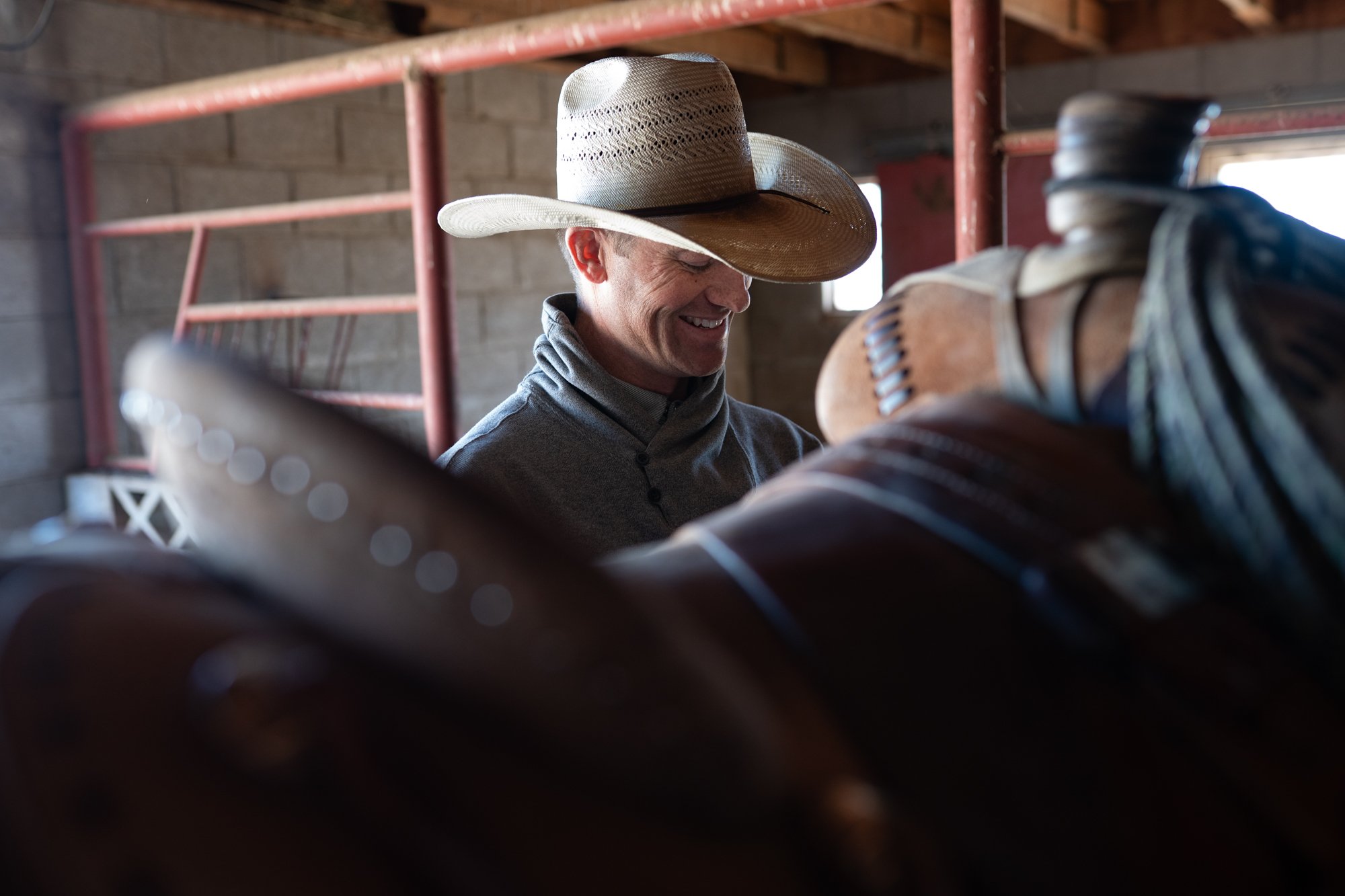 Cowboy smiles while preparing his horse inside the barn at Magnum Feedyard