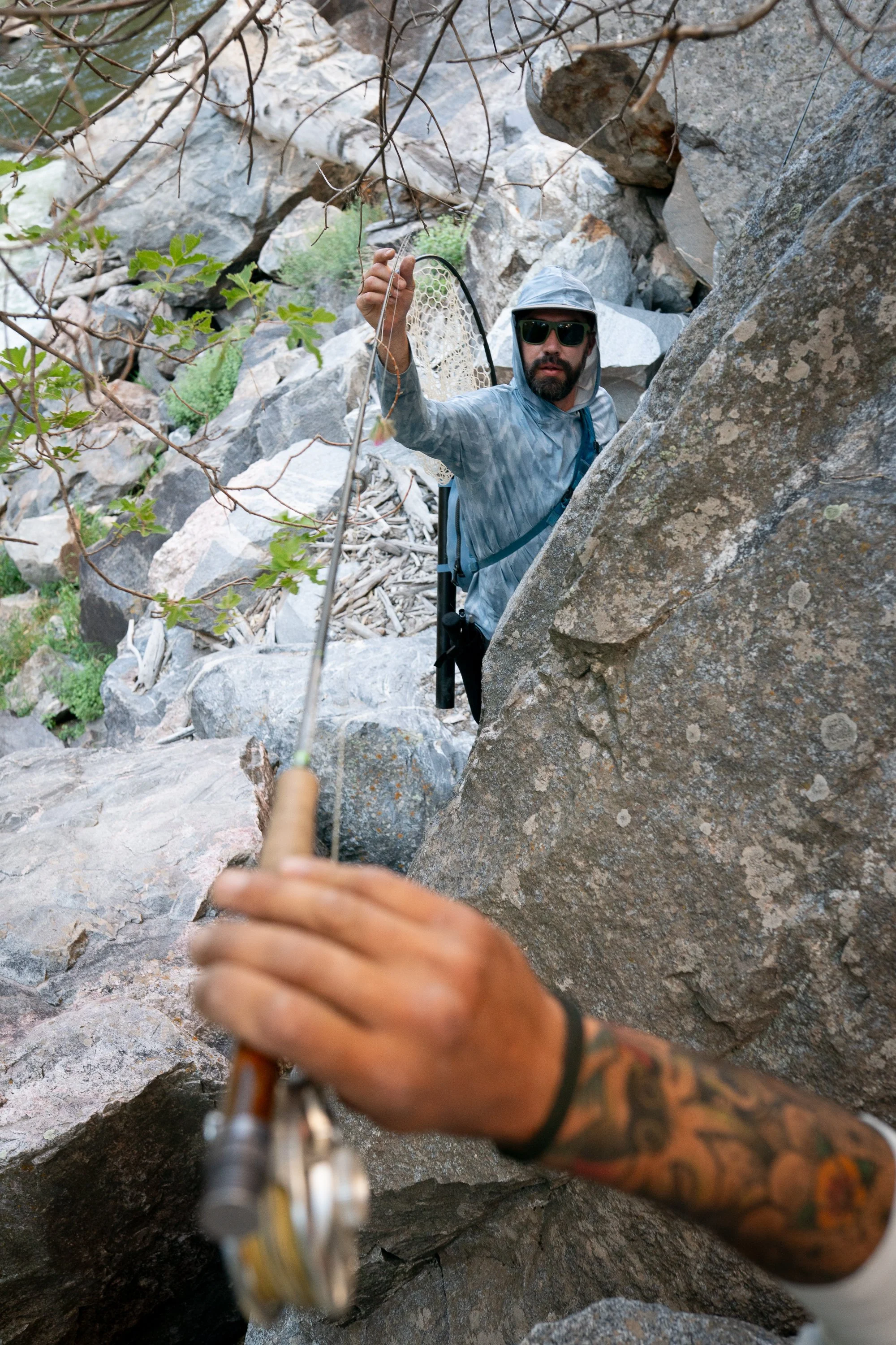 A fly angler reaches through canyon rocks while navigating tight terrain in Black Canyon.