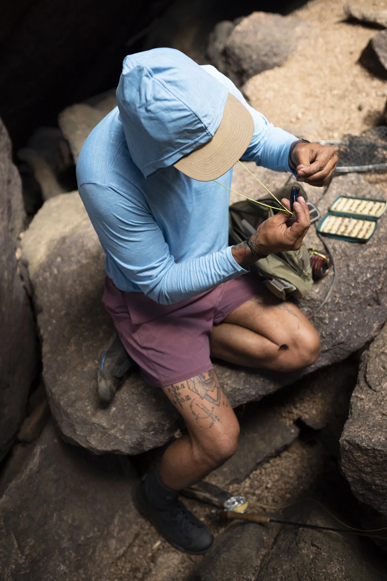 A fly fisherman rigs up his rod while sitting on rocks in Cheesman Canyon near Deckers, Colorado