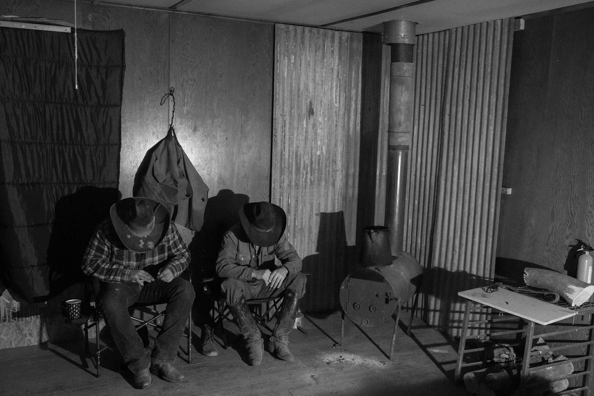 Cowboys sitting inside a dimly lit bunkhouse after a long day on a working ranch