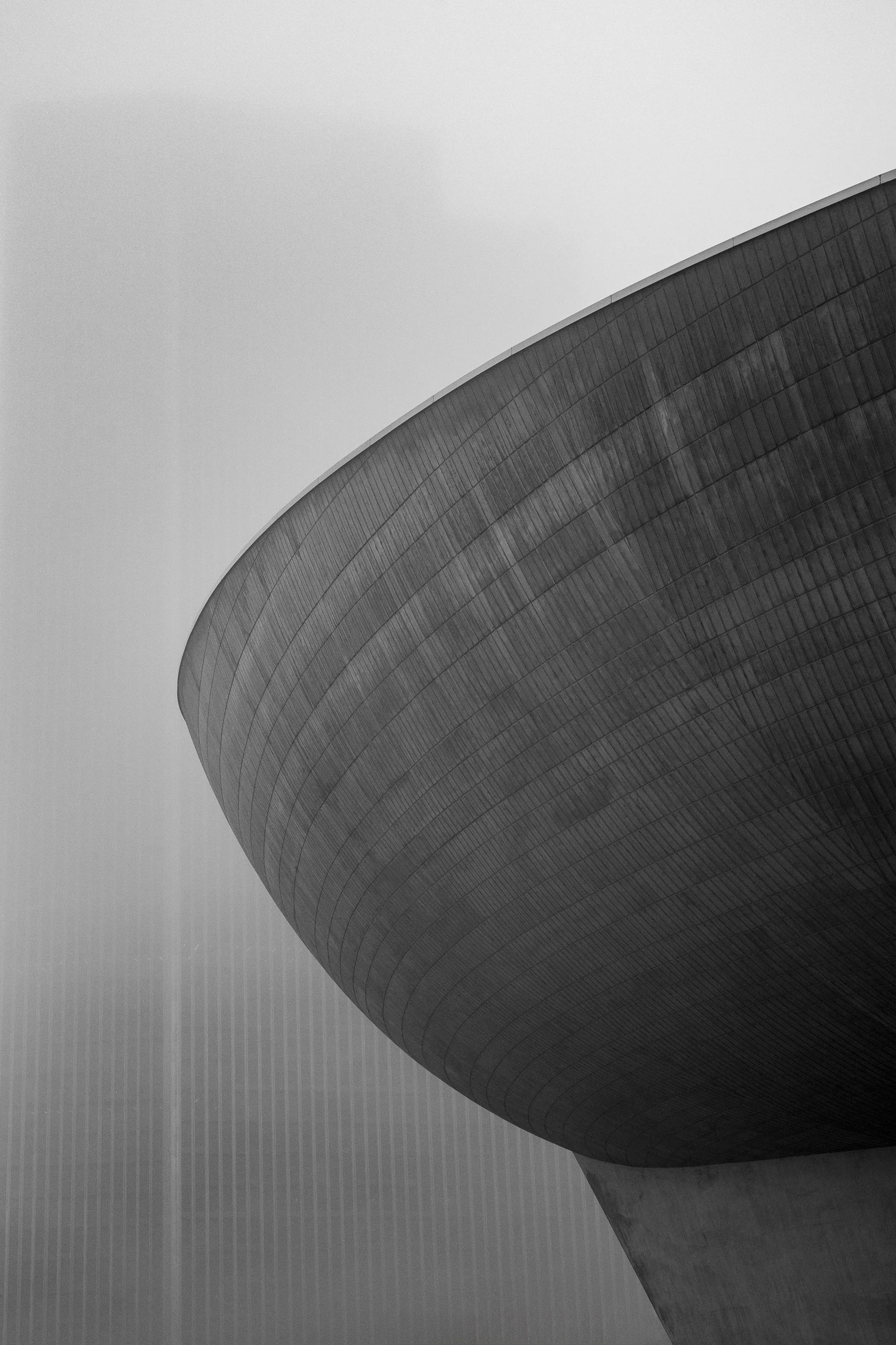 Black and white photograph of The Egg in Albany showing its curved concrete form fading into fog
